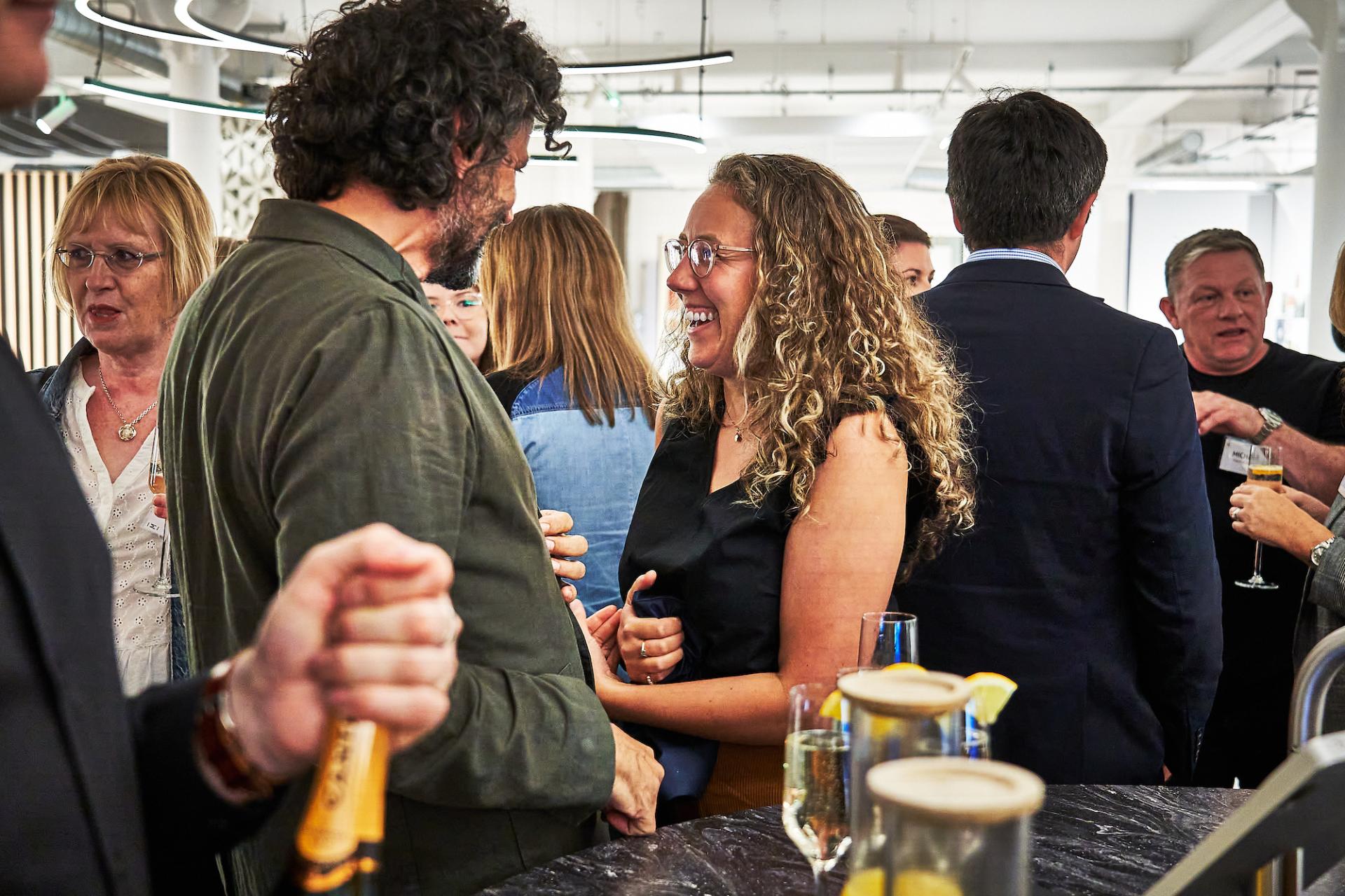 Celebrating the 42 Roles podcast, attendees engage in lively conversations at a networking event in a stylish setting.