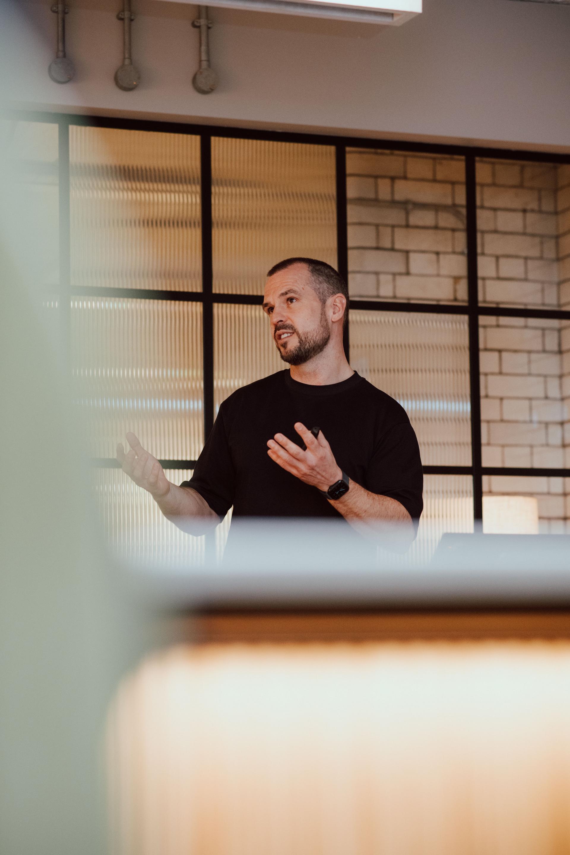 A speaker passionately discussing creative collaboration in interior design with students from Manchester Academy.