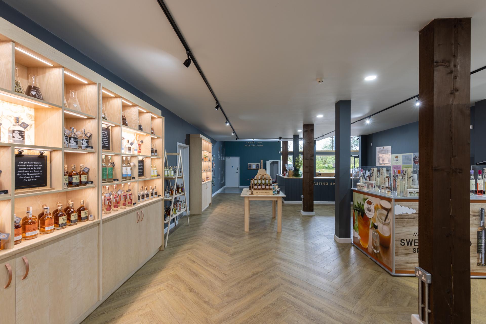 Modern interior of The English Spirit Distillery showcasing a tasting area with various spirits and liqueurs on display.