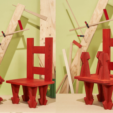 Vibrant red wooden chairs designed by Dharma Taylor and Paul Smith, showcasing innovative carpentry against a green backdrop.