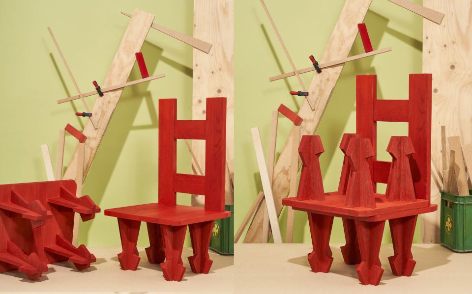 Vibrant red wooden chairs designed by Dharma Taylor and Paul Smith, showcasing innovative carpentry against a green backdrop.