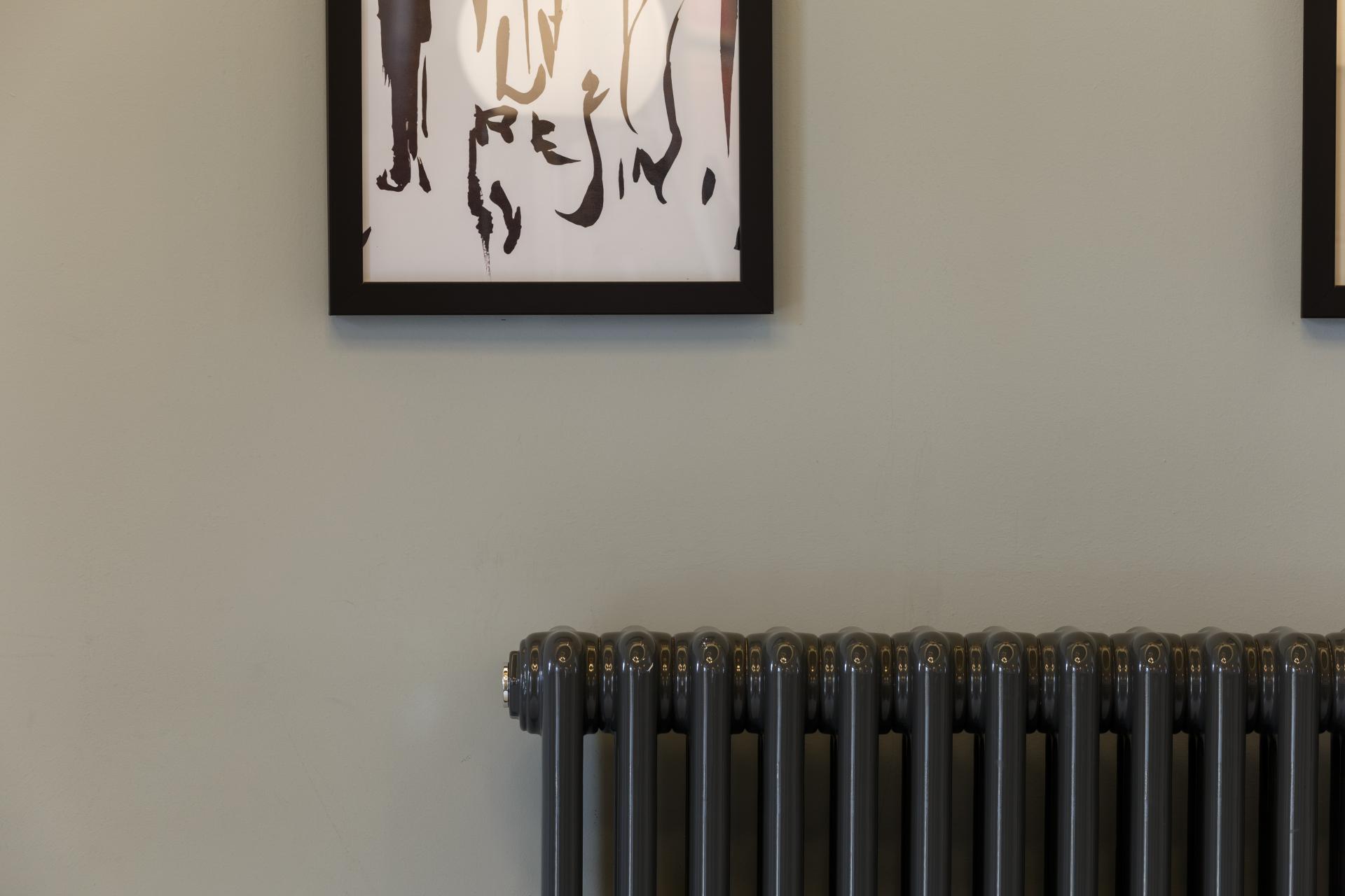 Heritage-inspired interior featuring framed artwork and a vintage-style radiator against a softly colored wall.