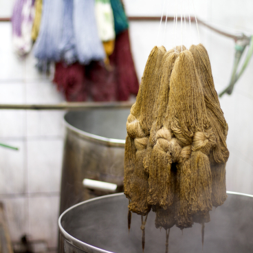 Skeins of natural wool being dyed in large metal pots, part of the crafting process for Carolina Palombo’s Tutura chair.