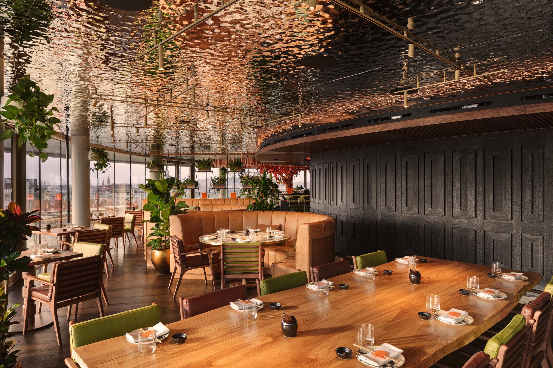 Luxurious dining area at W Hotel Edinburgh featuring vibrant plants, elegant furnishings, and panoramic city views.