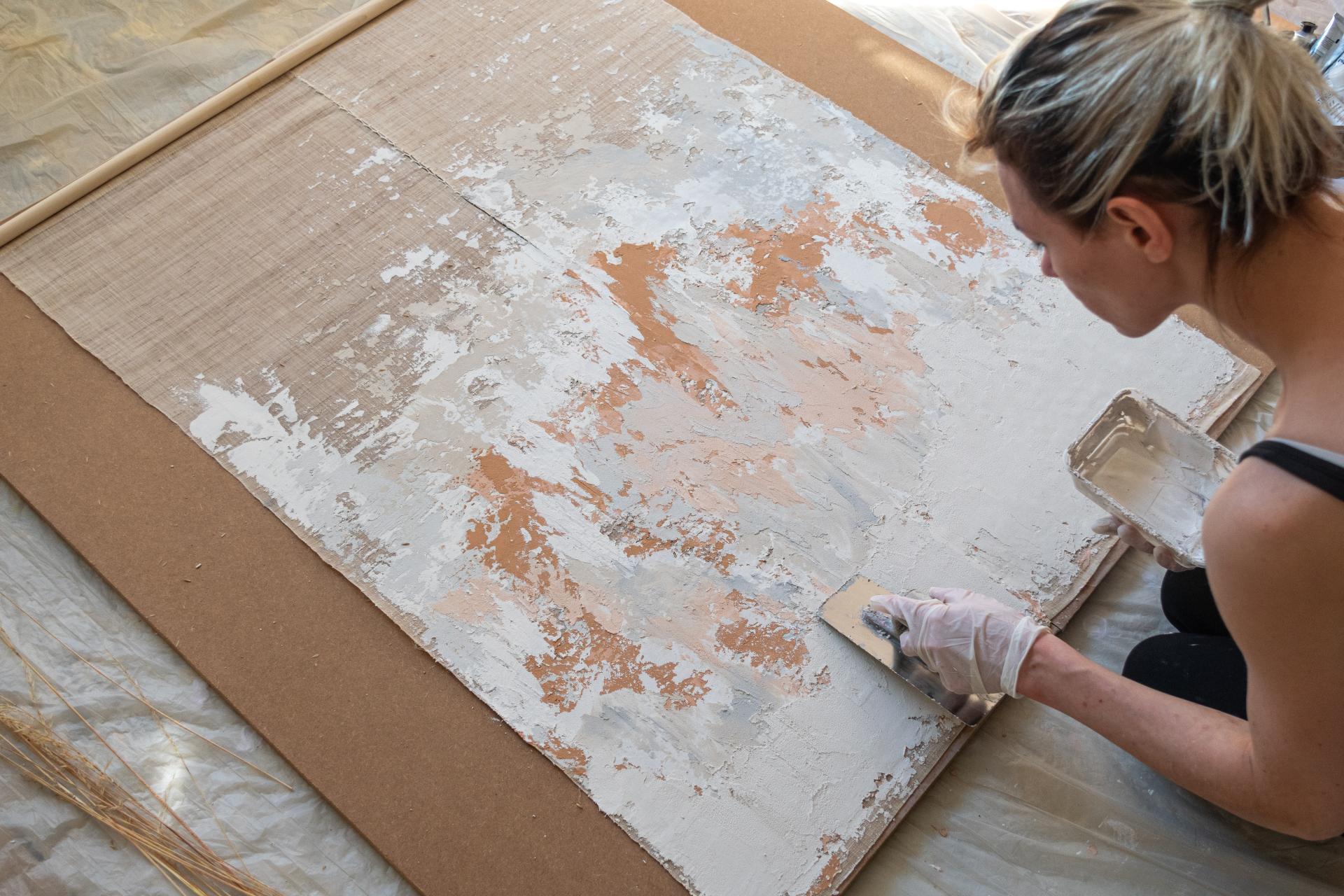 Artisan applying a unique plaster finish on a textured surface, showcasing Vacarda Design's innovative craftsmanship techniques.
