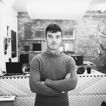Giles Miller poses in his studio, showcasing innovative design surfaces and a creative workspace atmosphere.