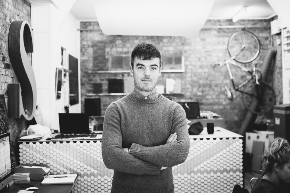 Giles Miller poses in his studio, showcasing innovative design surfaces and a creative workspace atmosphere.