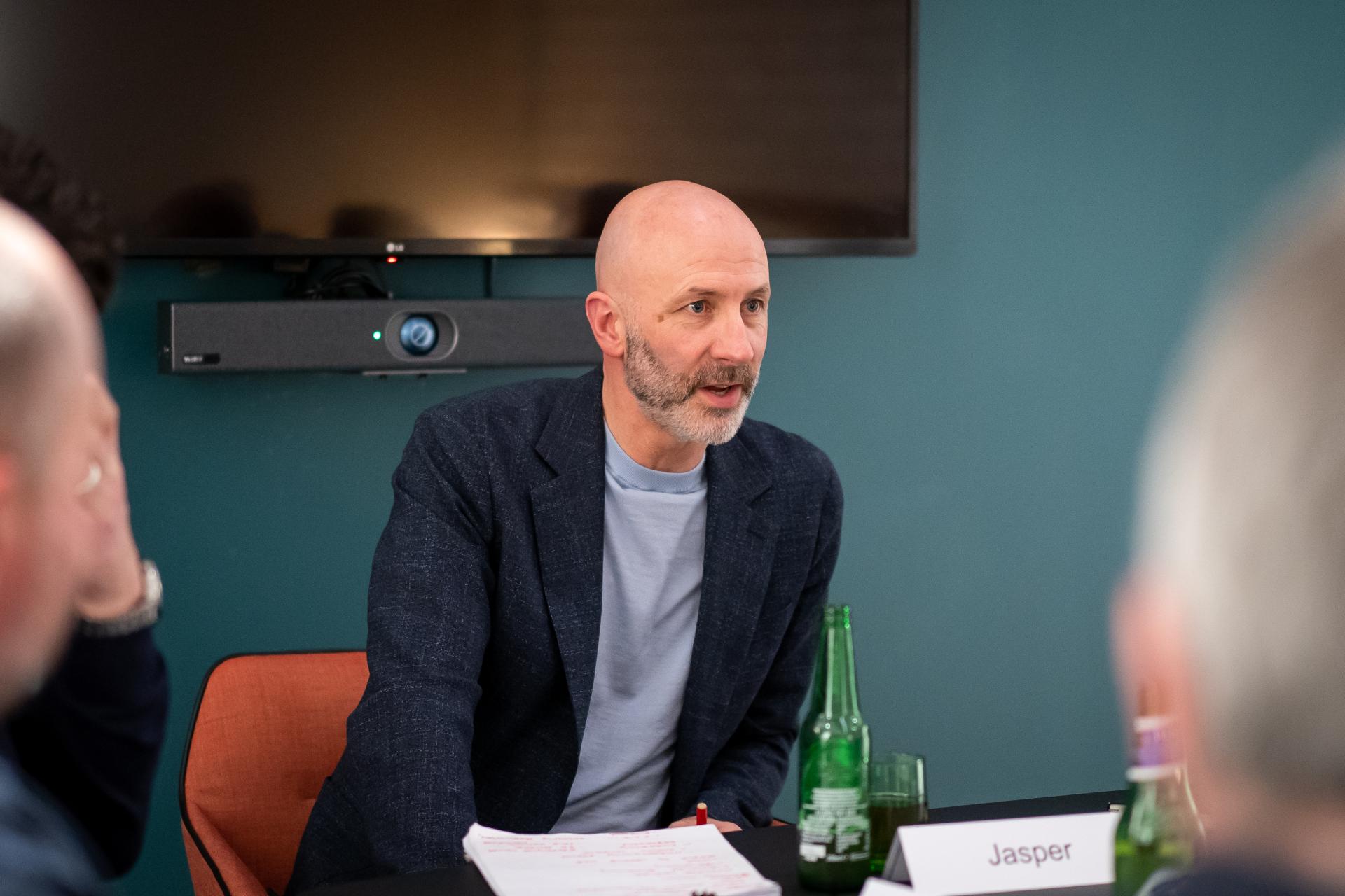 Discussion on sustainability trends at a seminar, featuring a man speaking at a table with drinks.