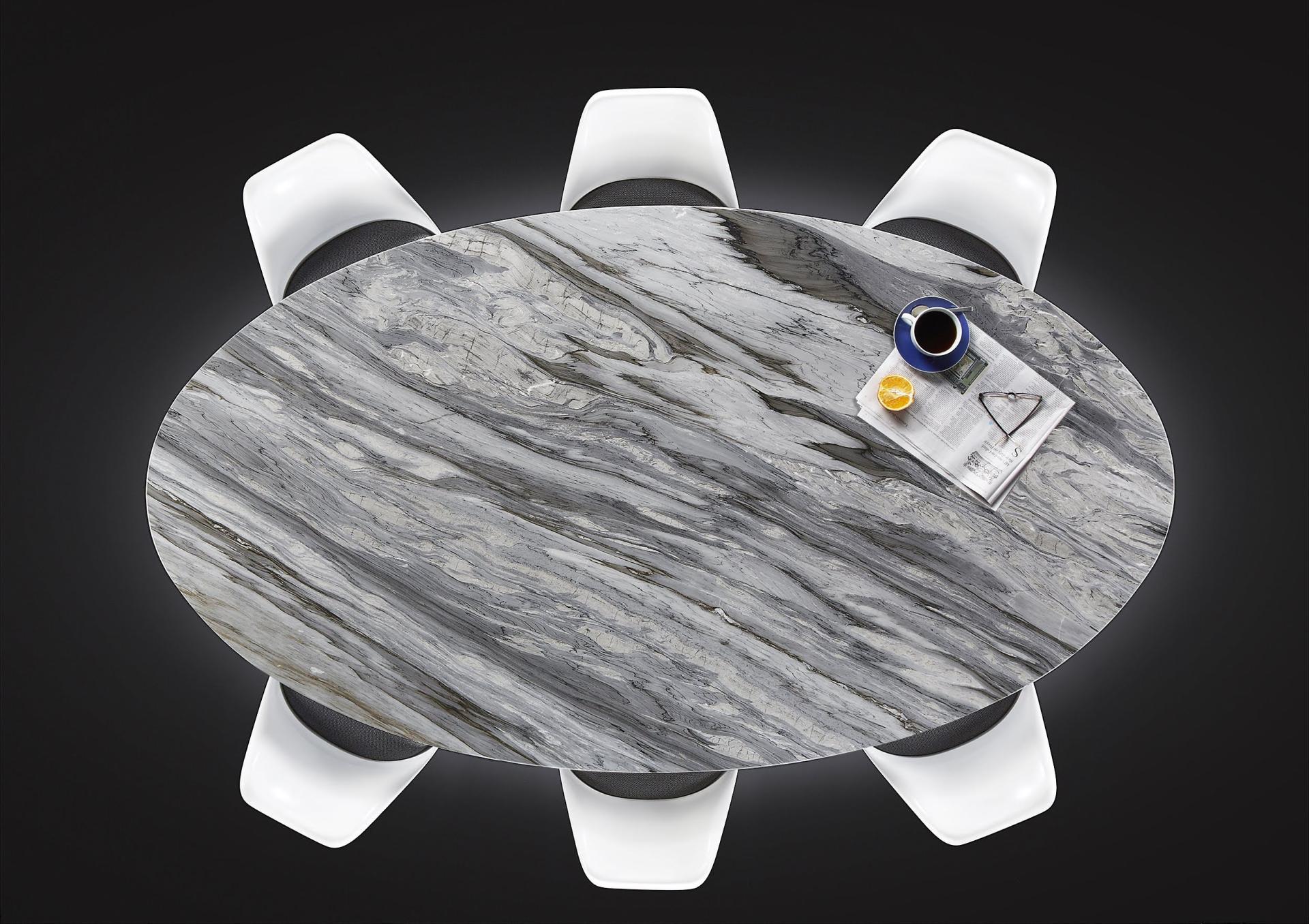 Elegant oval marble dining table with modern chairs, featured in exclusive editions at London Design Festival.