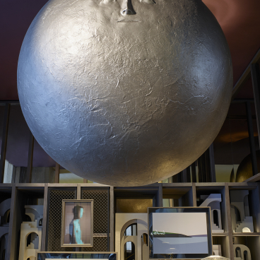 Theatrical interior of Leicester Square hotel featuring a large, artistic sphere and various framed artworks against a modern backdrop.
