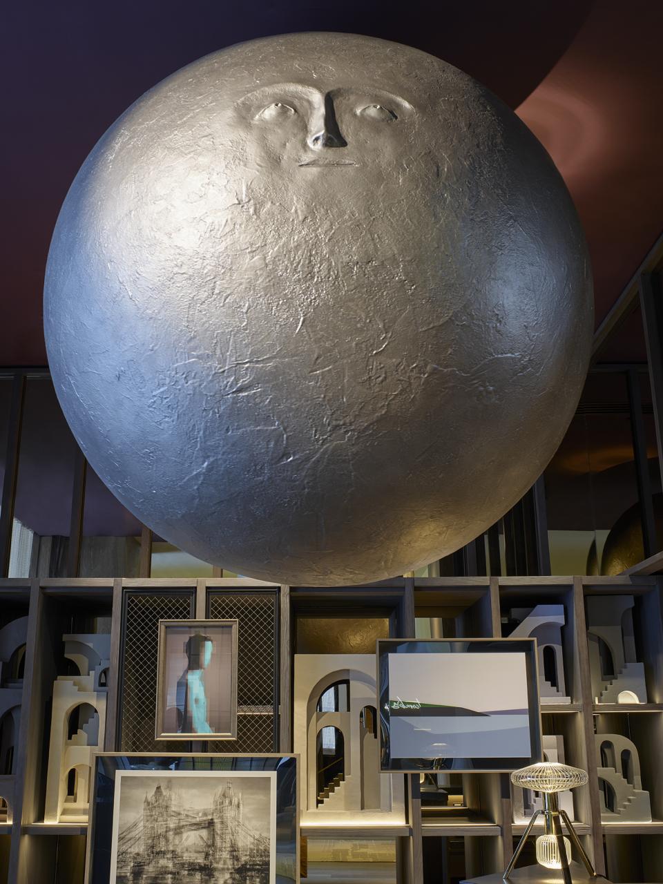 Theatrical interior of Leicester Square hotel featuring a large, artistic sphere and various framed artworks against a modern backdrop.