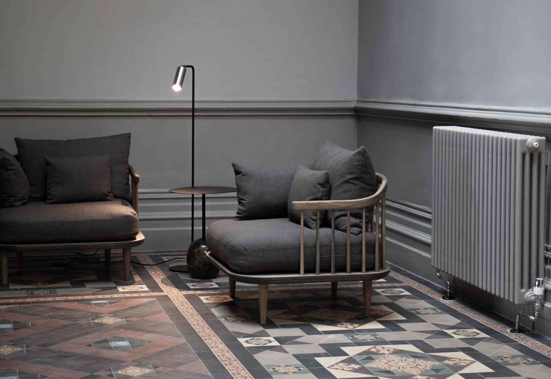Stylish interior featuring modern gray sofas, a sleek floor lamp, and patterned tiles, showcasing Youth Studio's design aesthetics.