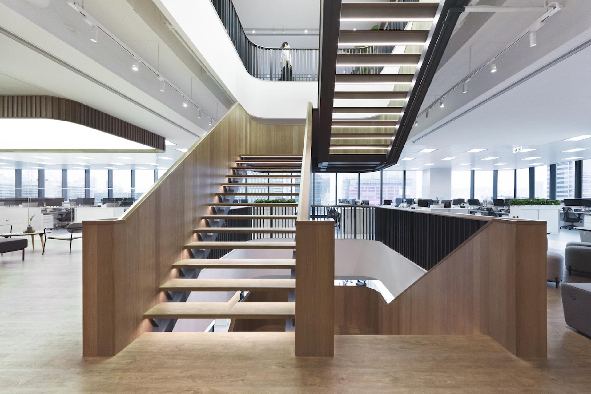 Modern office interior featuring a striking wooden staircase and an open workspace designed by Bean Buro.