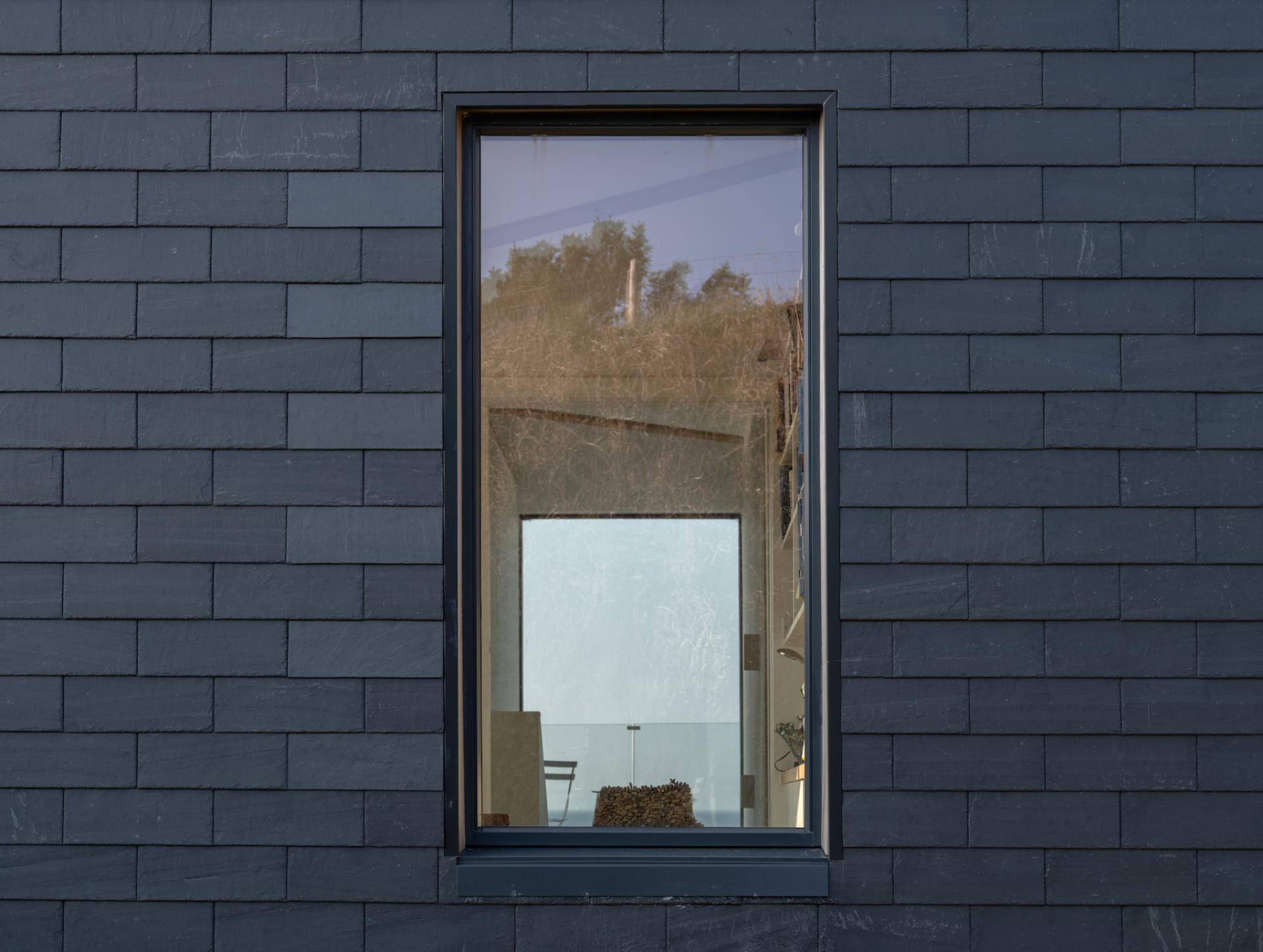 Modern coastal home window featuring CUPACLAD 101 Logic slate cladding, showcasing natural materials and contemporary design.