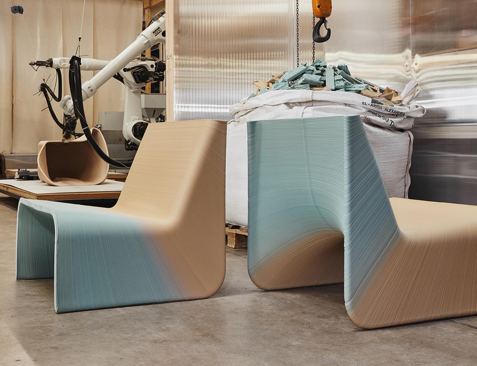 Two unique Ermis chairs in earthy tones, crafted from recycled materials, displayed in a design studio environment.