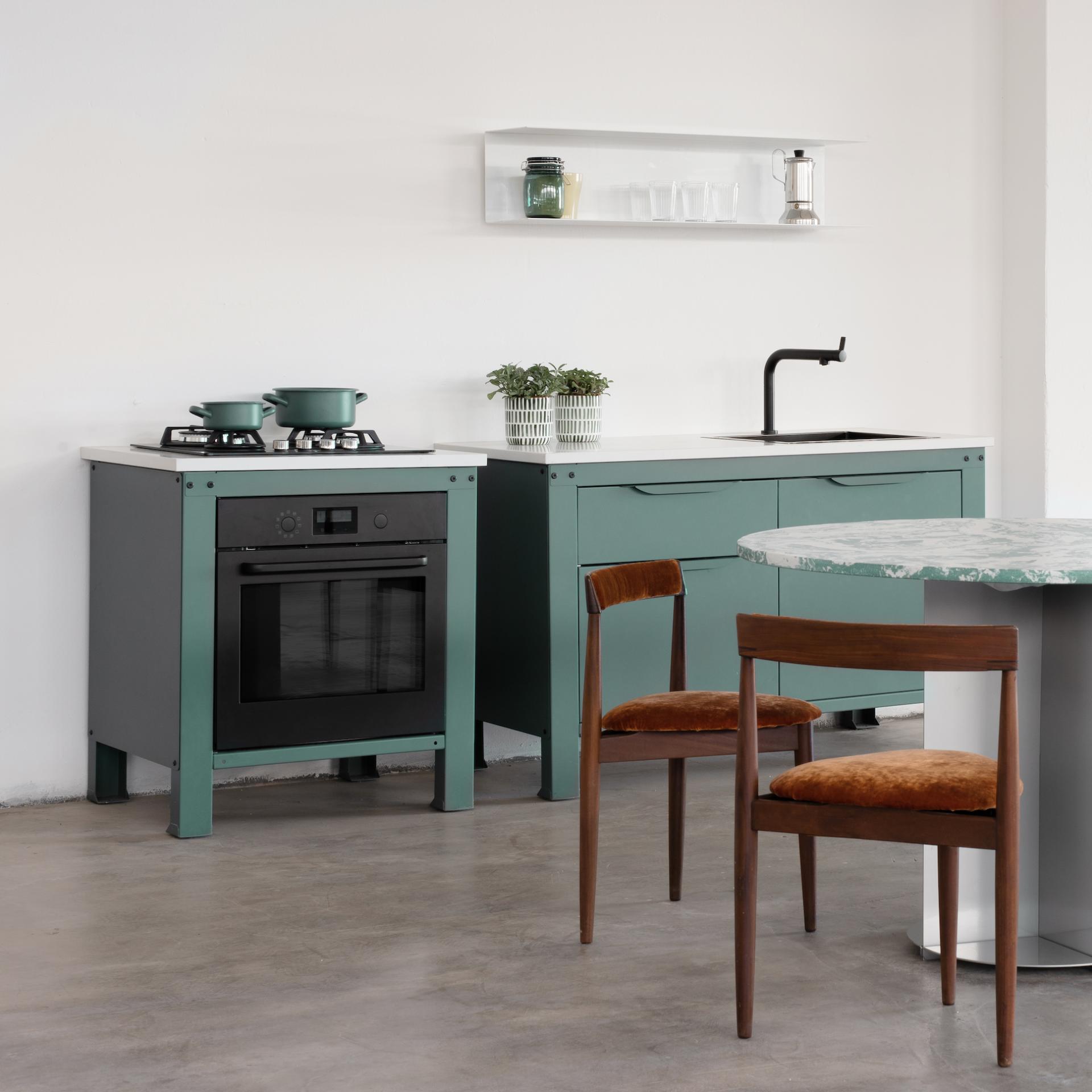 Modern kitchen featuring unique green cabinets, gas stove, brown chairs, and minimalist decor, highlighting beauty in concrete design.