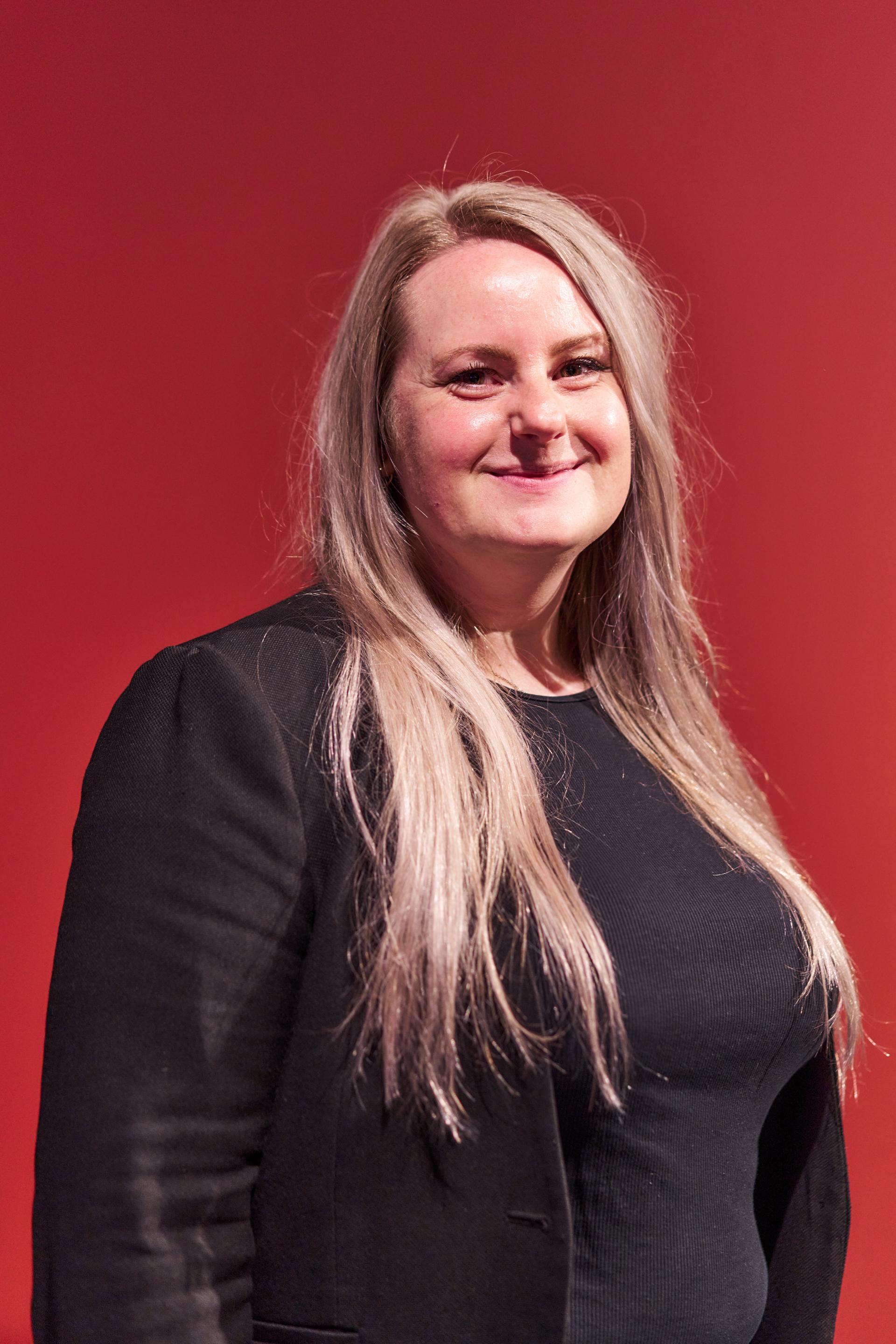 Speaker at Material Source Studio event discussing Glasgow's residential mix, set against a vibrant red background.