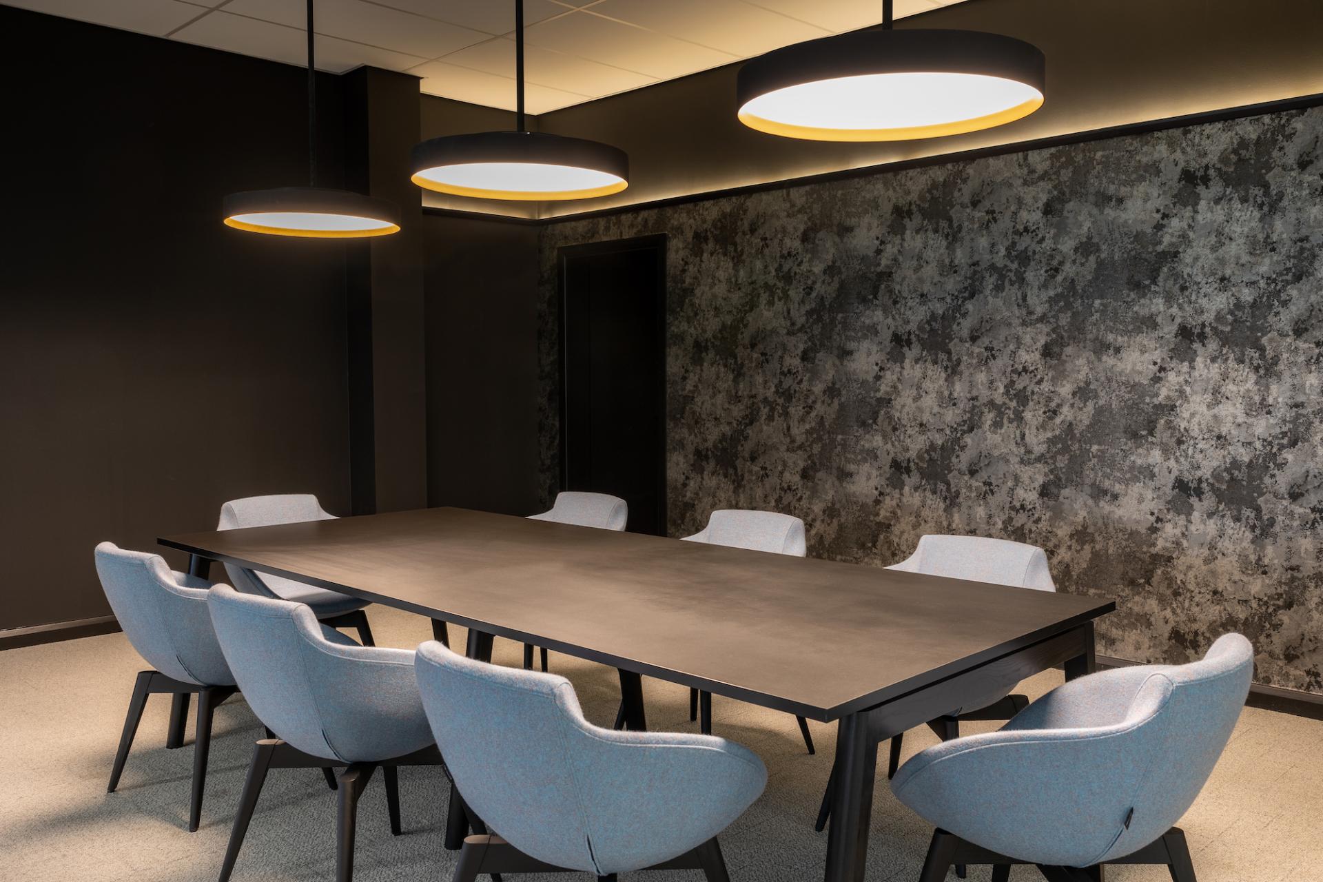 Stylish conference room featuring a modern black table and eight light blue chairs, designed by M1NT Studio.