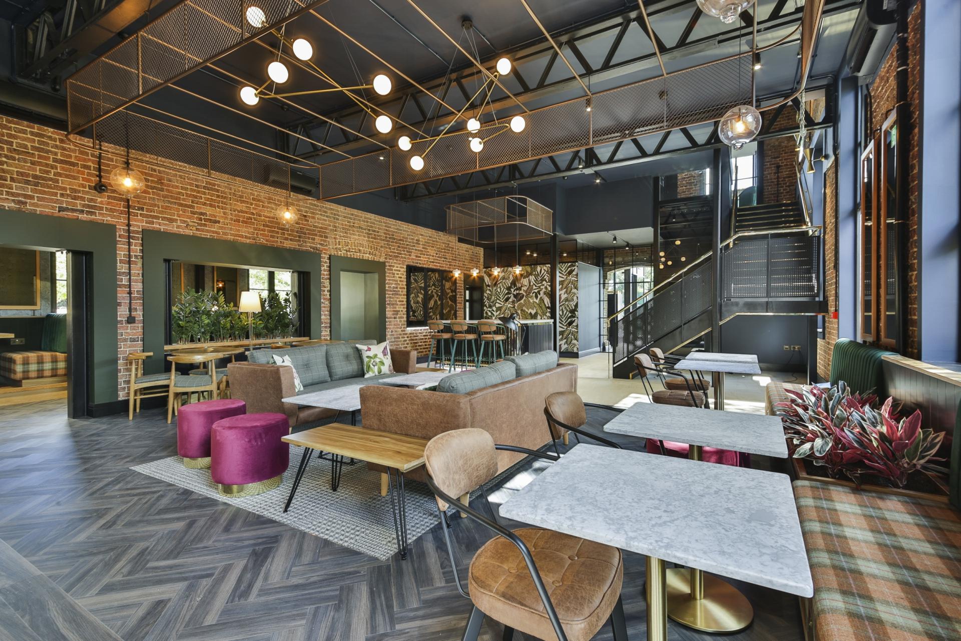 Modern interior design featuring a spacious café area with brick walls, stylish furniture, and ambient lighting in Manchester.