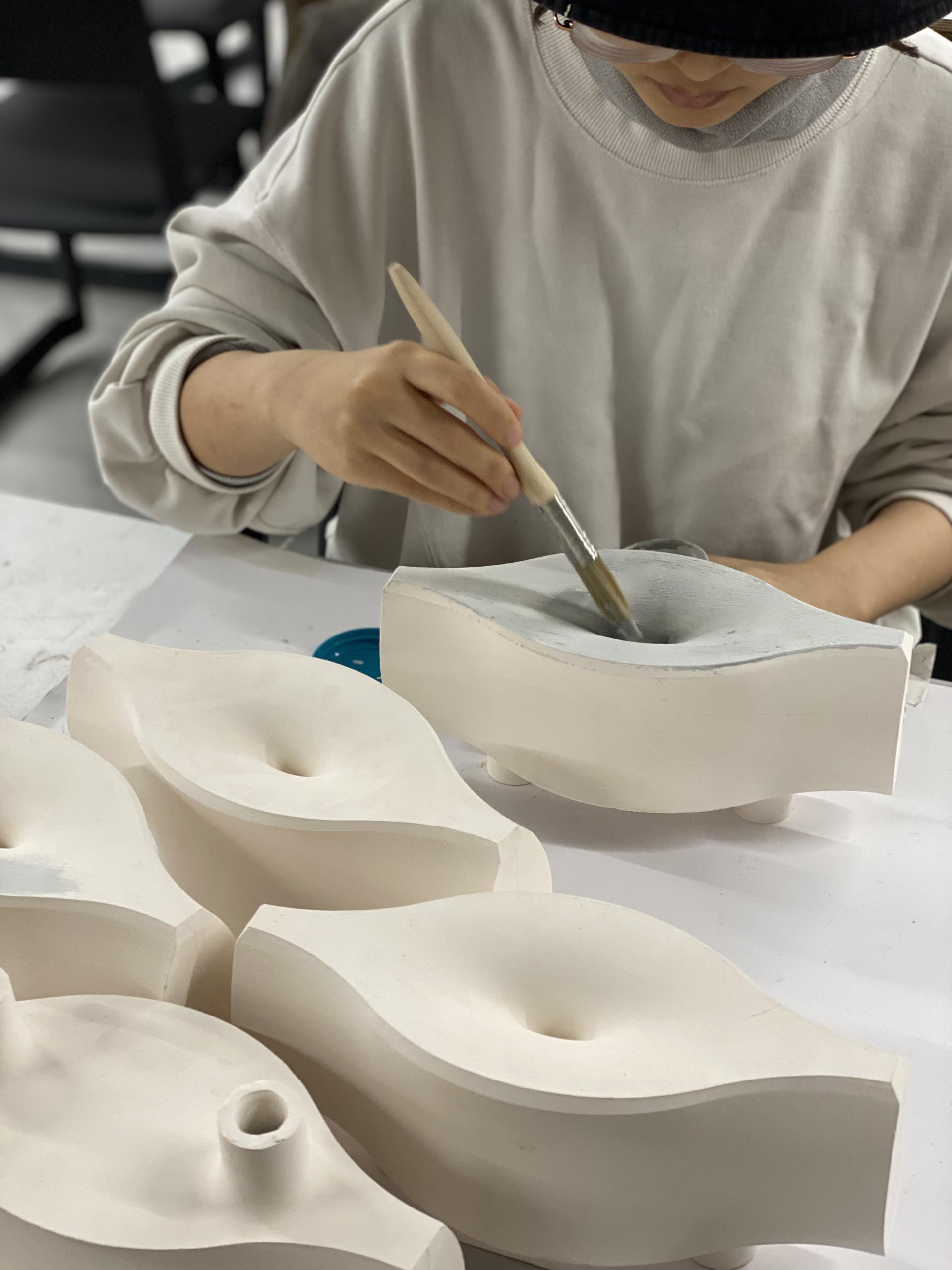 A student paints architectural models designed to absorb noise pollution at the Bartlett School of Architecture.