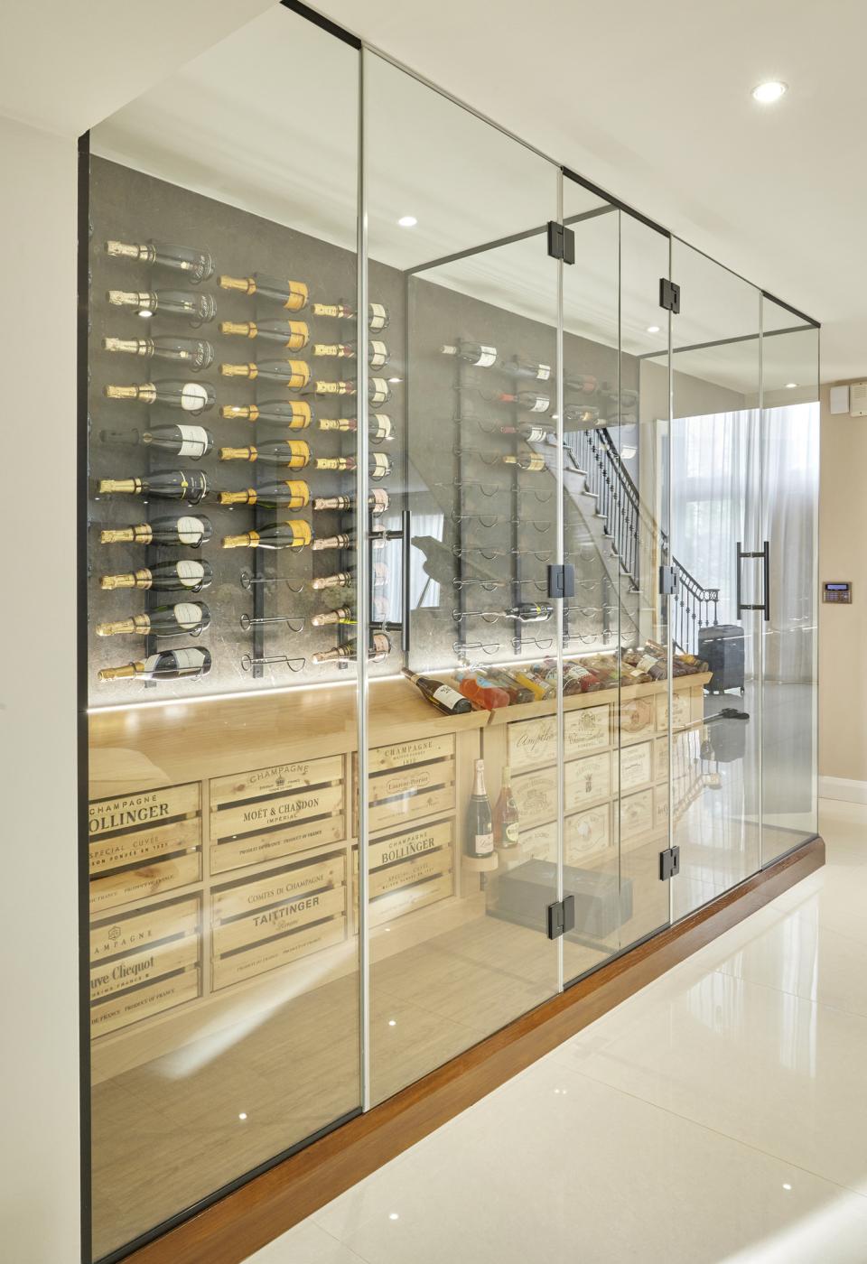 Elegant wine room featuring a glass-enclosed display with an array of premium bottles and wooden crates in a modern setting.