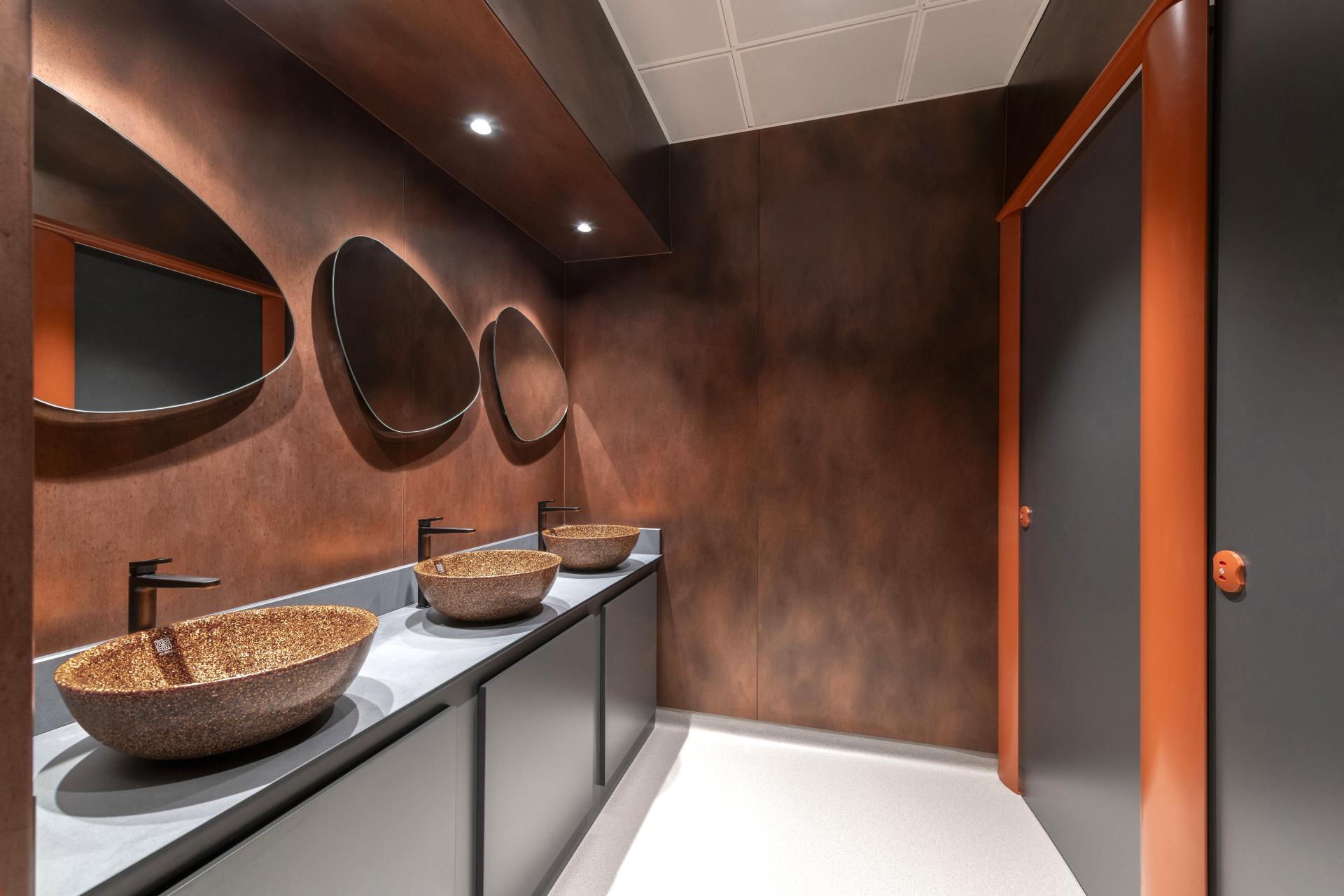 Contemporary washroom featuring elegant vessel sinks, dark bronze walls, and stylish mirrors, designed for collaboration at Material Source Studio.