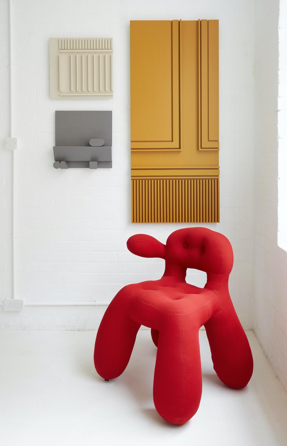 Avant-garde red chair design featured at House on Mars, complemented by contemporary art pieces on the wall.