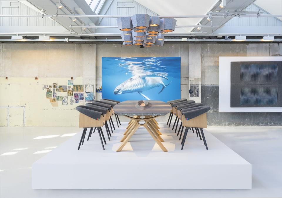 Sustainable furniture displayed in a modern showroom featuring artwork of a whale and stylish wooden dining chairs.