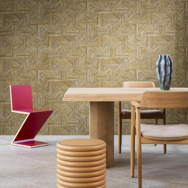 Modern dining area featuring a unique pink chair, wooden table, cylindrical stool, and textured golden wall inspired by Tangram designs.