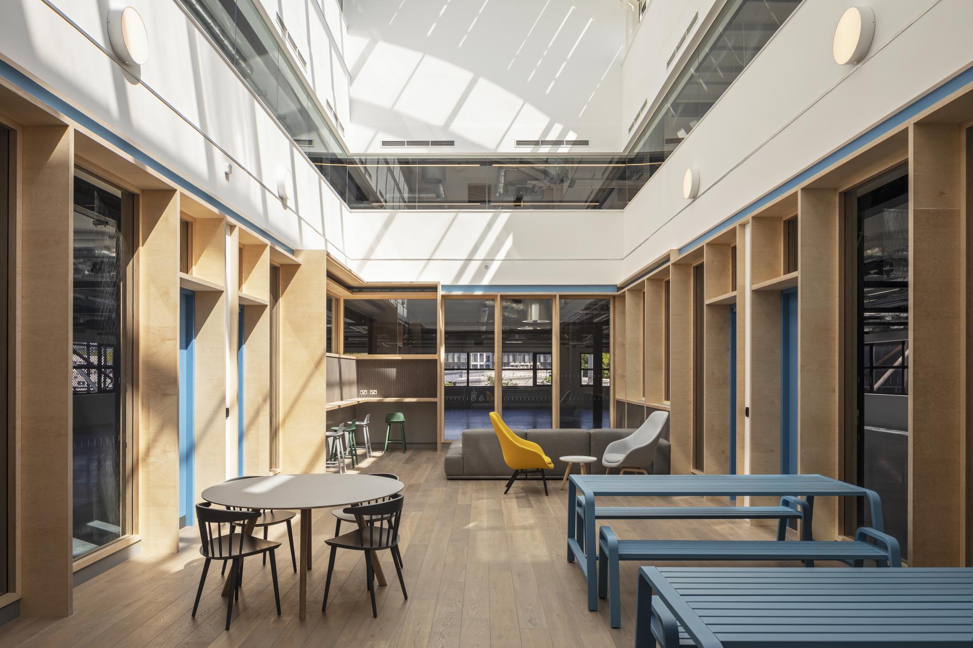 Bright, modern office interior featuring wooden finishes, colorful furniture, and abundant natural light streaming in.