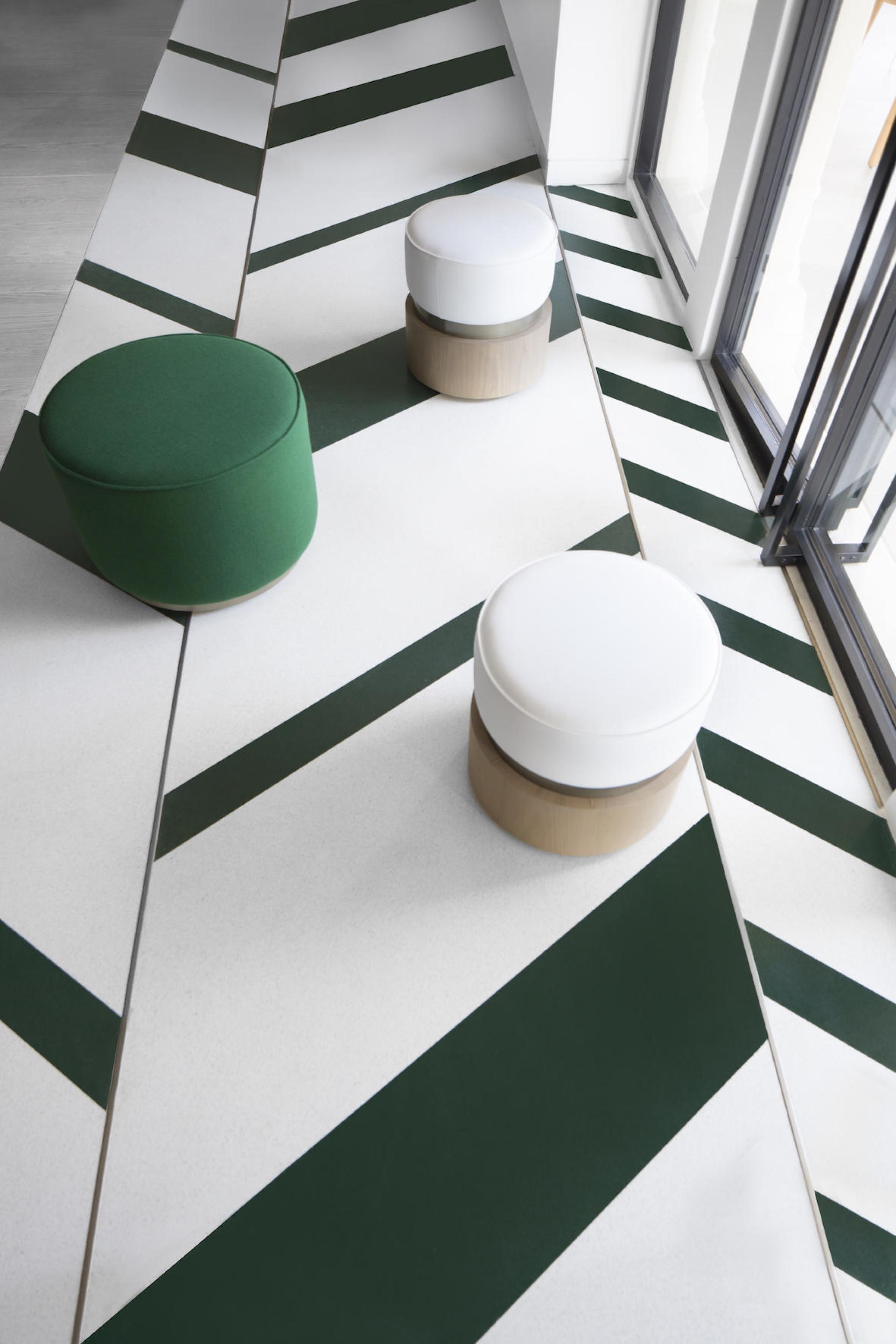 Stylish geometric seating in green and white hues on a vibrant patterned floor, showcasing modern interior design.