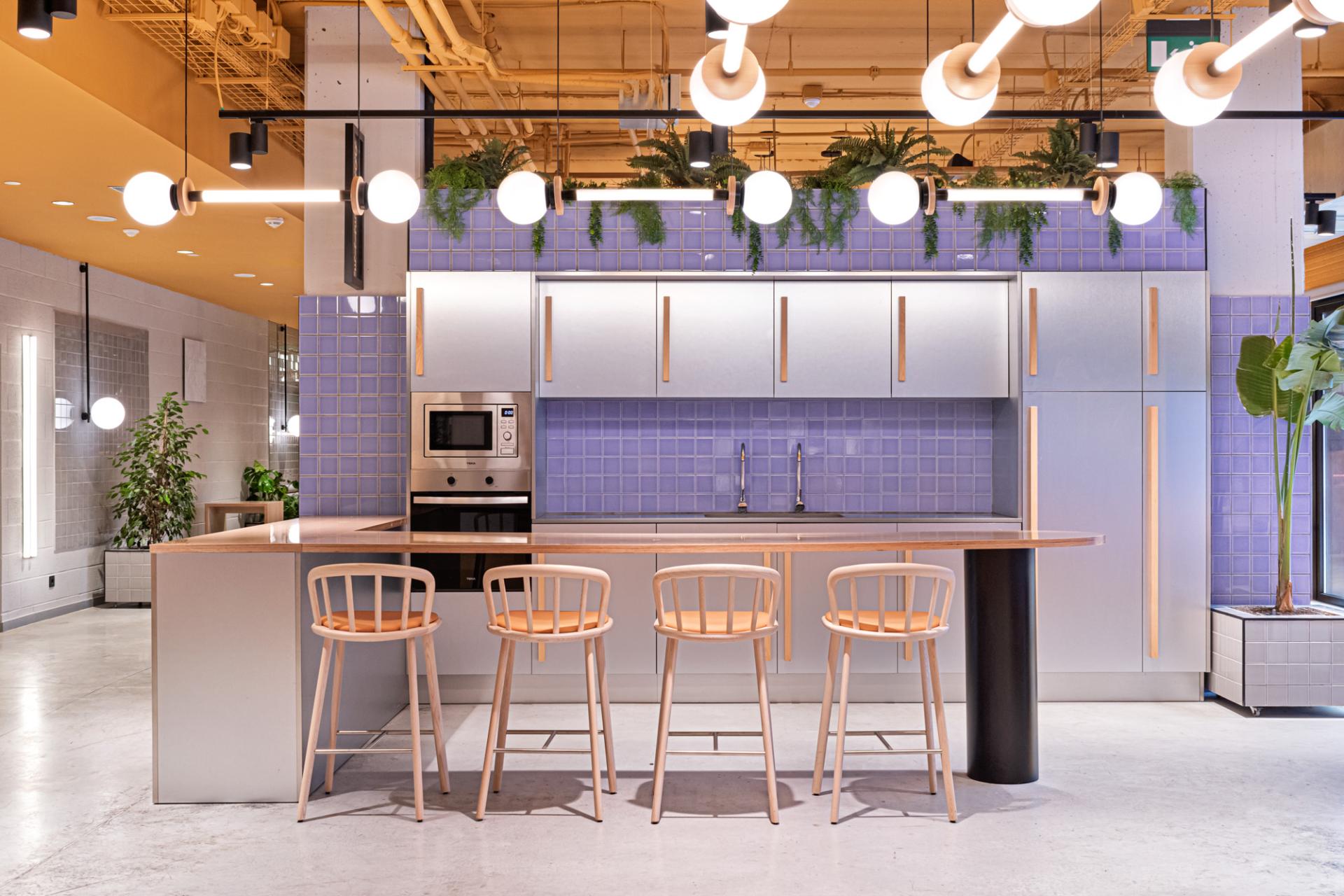 Modern open kitchen design in a student residence, featuring pastel tiles, stylish bar stools, and contemporary lighting.