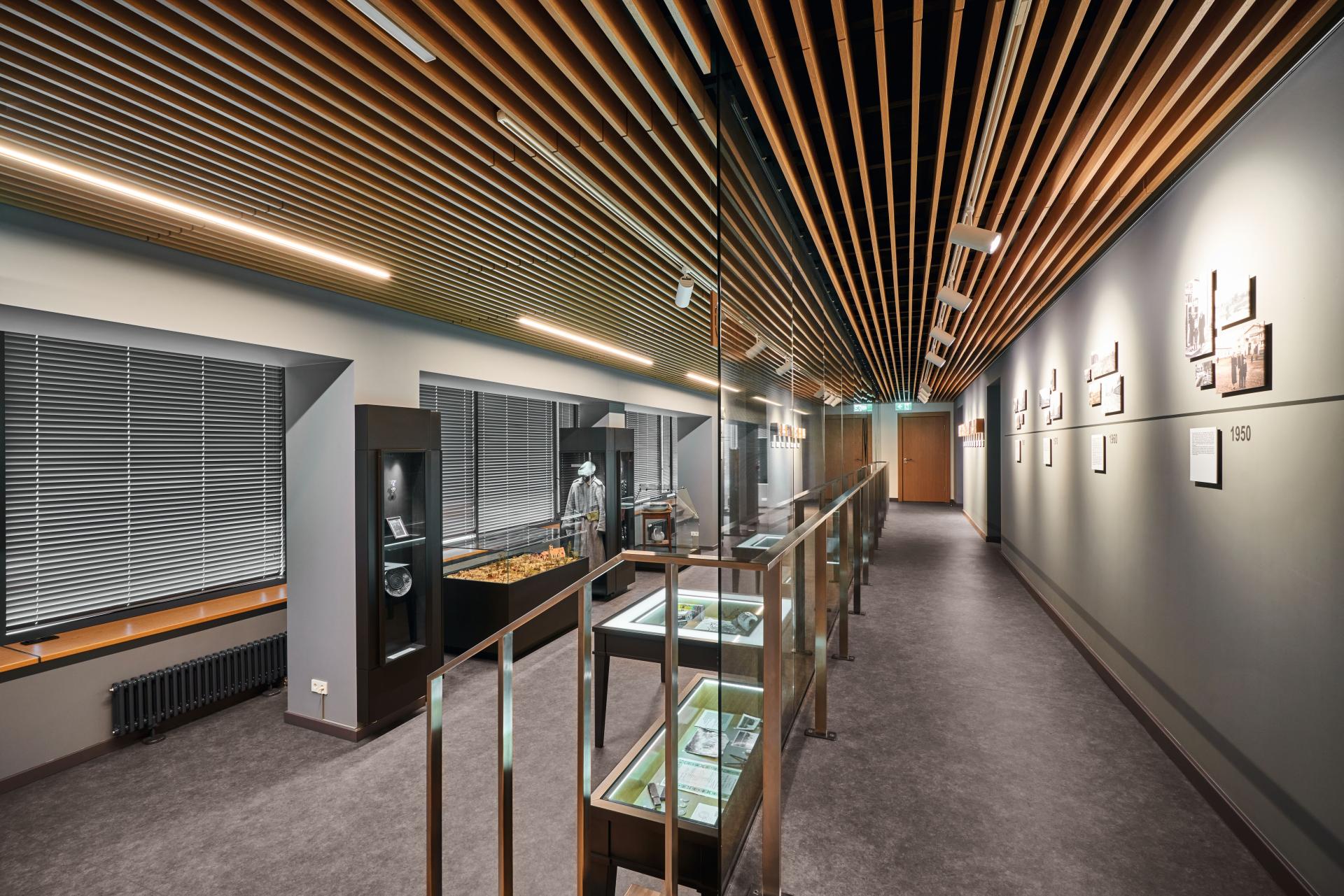 Modern hallway featuring adhesive-free safety flooring, showcasing display cases and artistic ceiling design.