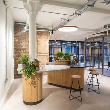 Modern welcome area of Material Source Studio in Manchester, featuring a stylish counter and lush greenery.
