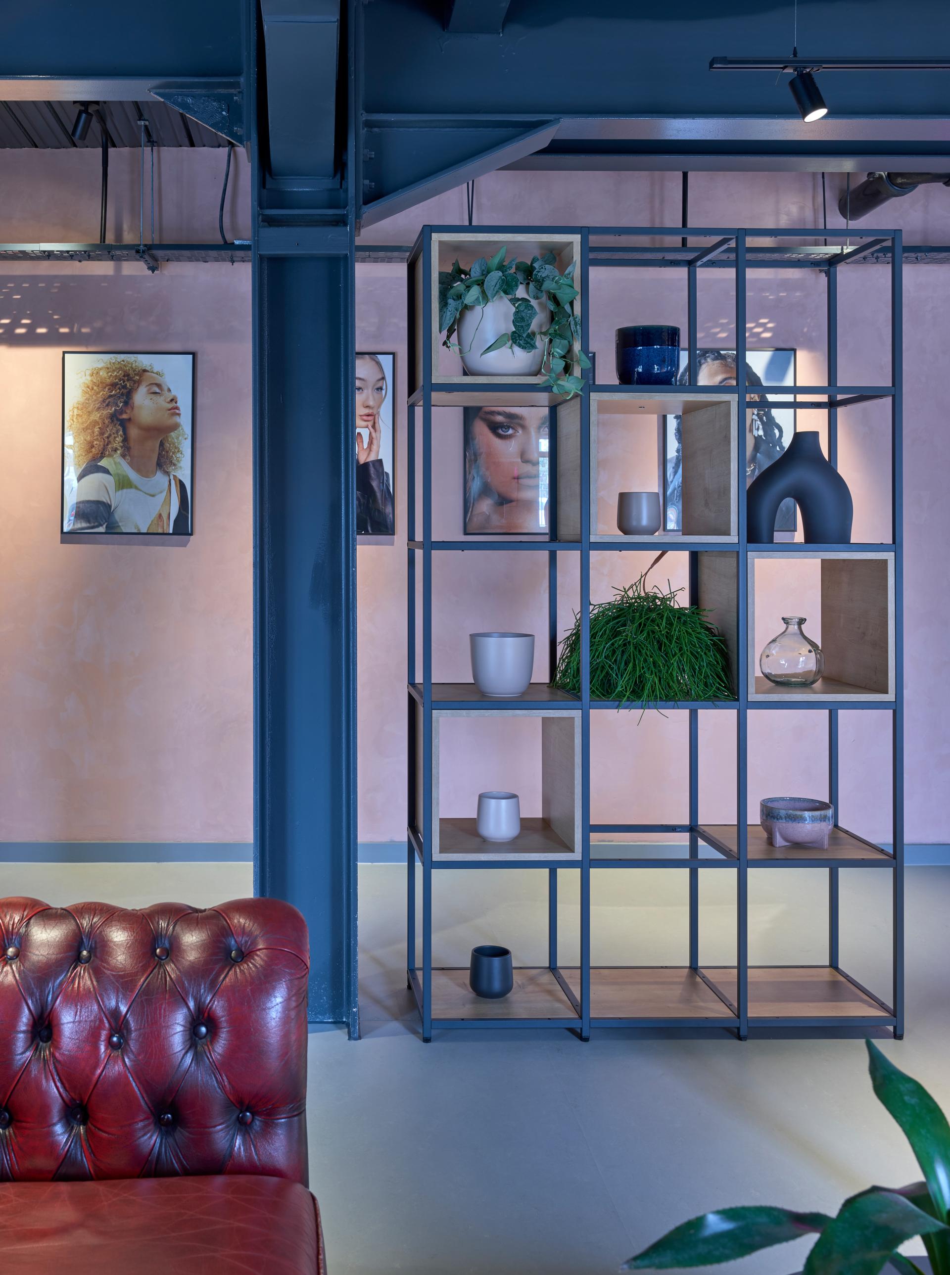 Stylish interior of J’adore Models HQ, featuring modern shelving, decorative plants, and vibrant artwork on pastel walls.