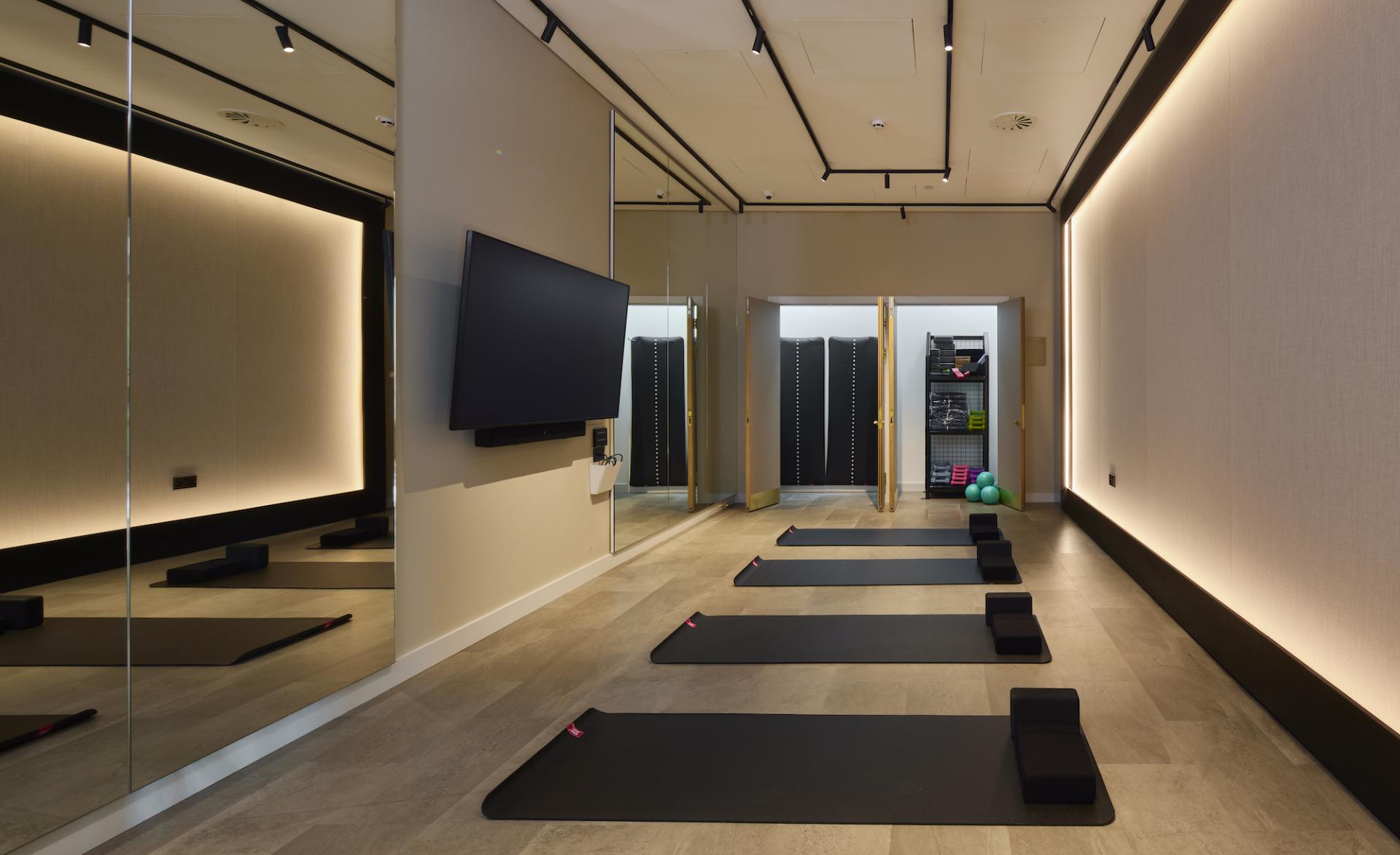 Modern residential amenity space at Novella featuring yoga mats, a television, and well-lit design elements.