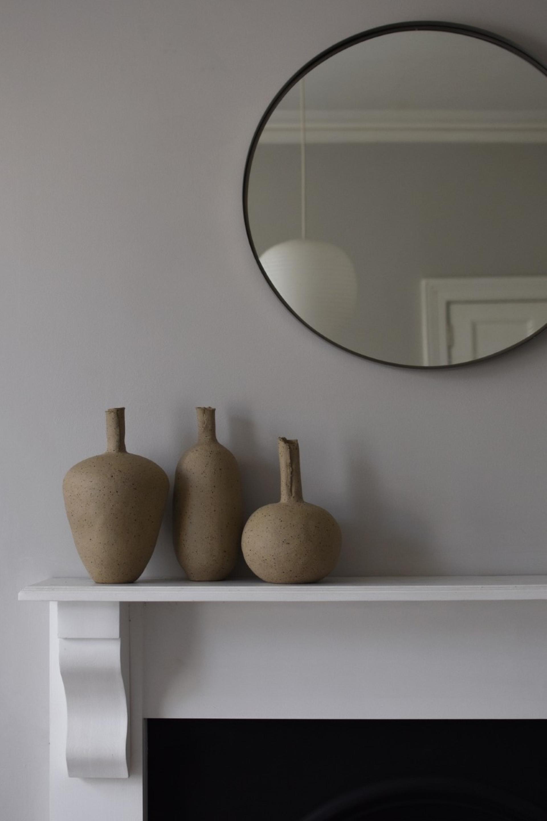 Three handmade ceramic vases in varying shapes and sizes adorn a white mantel, reflecting Bristol's creative craft scene.