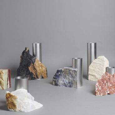 Stylish arrangement of raw stone sculptures and metallic cylinders reflecting the aesthetic of BLOC STUDIOS x Tableau collaboration.