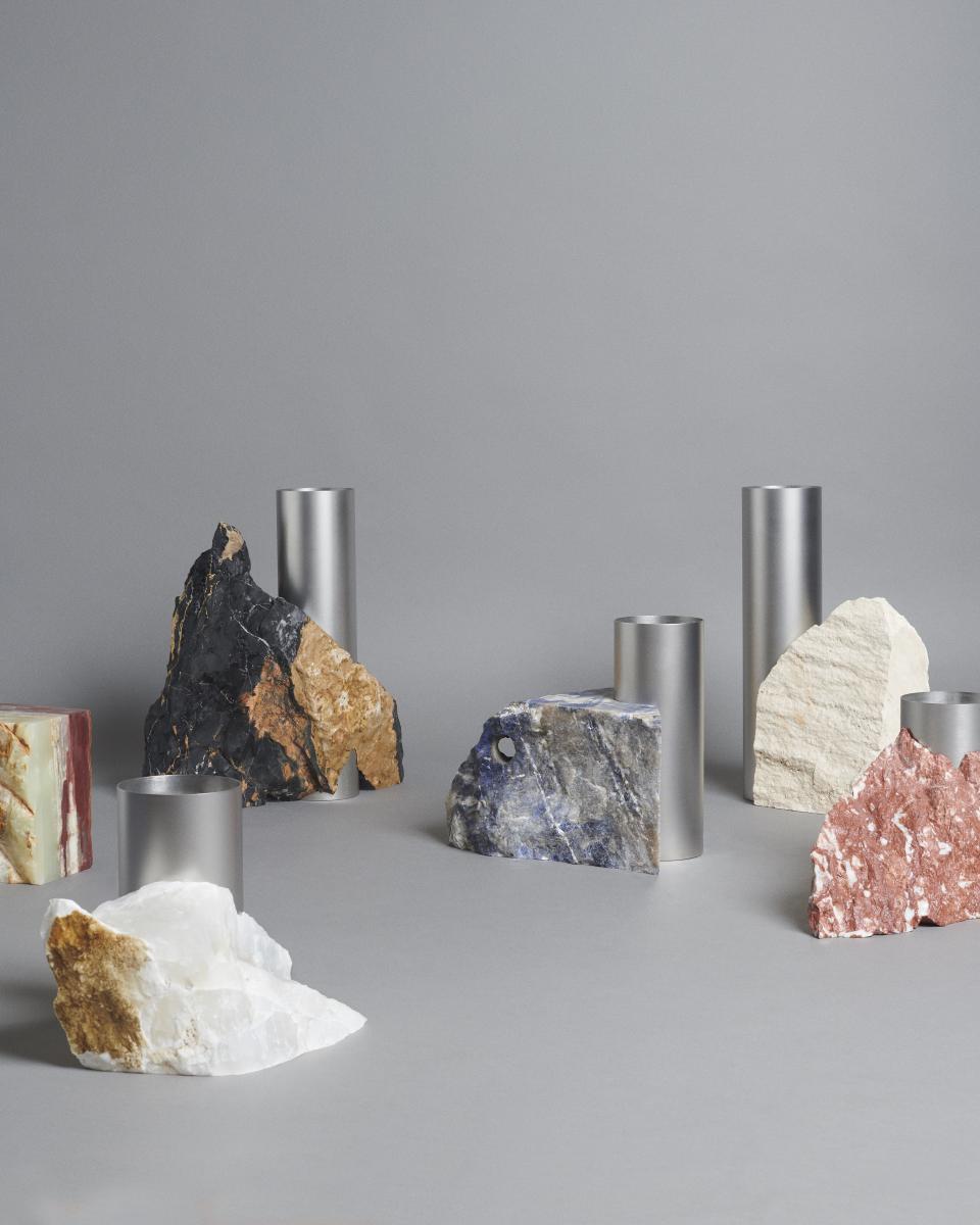 Stylish arrangement of raw stone sculptures and metallic cylinders reflecting the aesthetic of BLOC STUDIOS x Tableau collaboration.