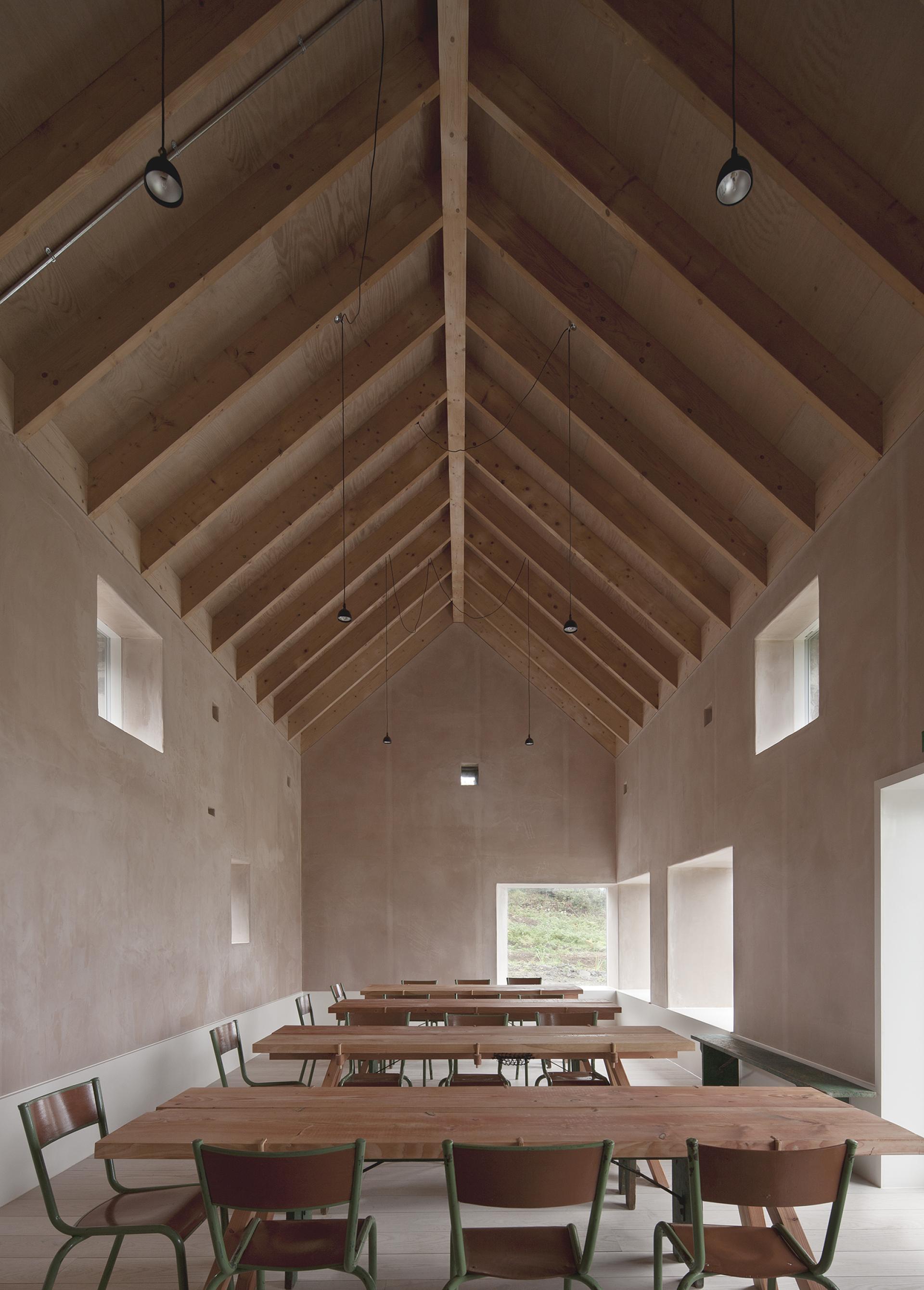 Interior of a renovated croft on the Isle of Mull, featuring natural wood beams and communal dining tables.