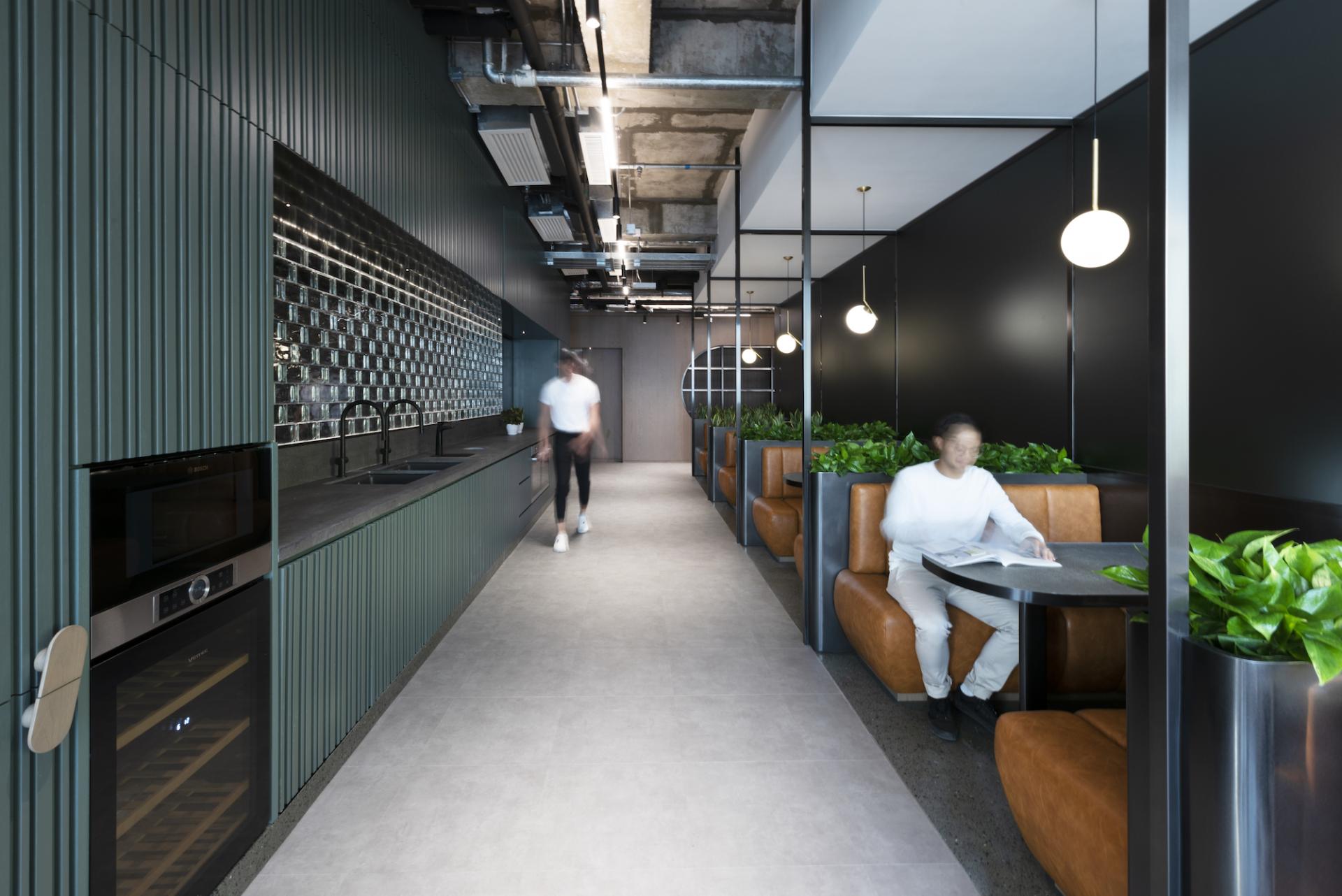 Modern office kitchen space at Warner Music Hong Kong featuring sleek design, greenery, and collaborative seating areas.