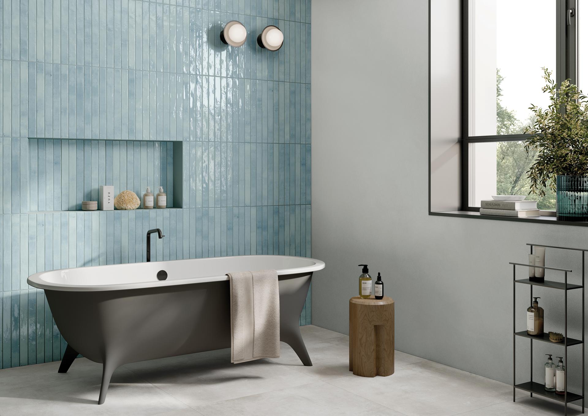 Elongated blue tiles from Grestec's Mastreta collection grace a modern bathroom featuring a freestanding bathtub and stylish fixtures.