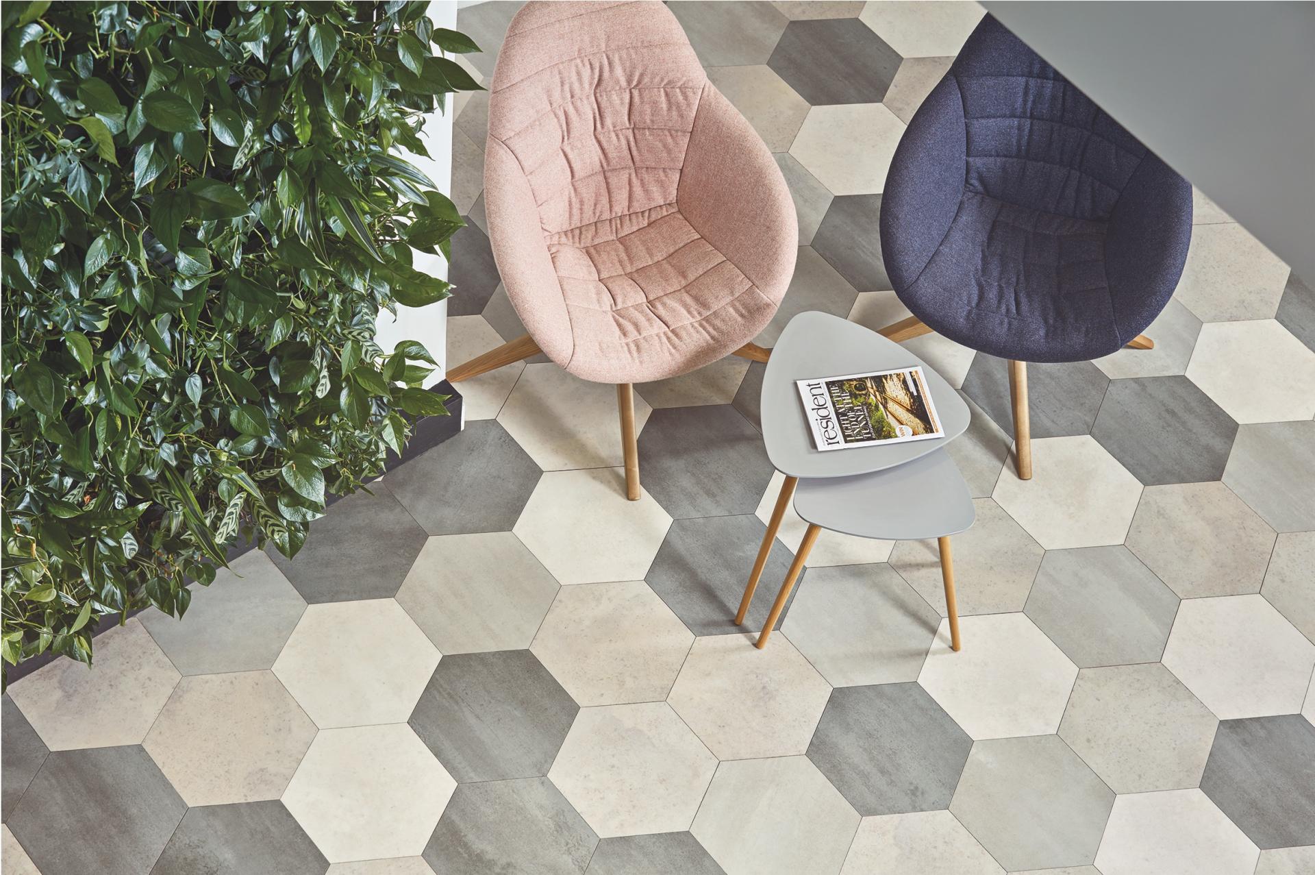 Stylish chairs and a modern table on hexagonal tiled flooring, surrounded by vibrant greenery in a contemporary studio setting.