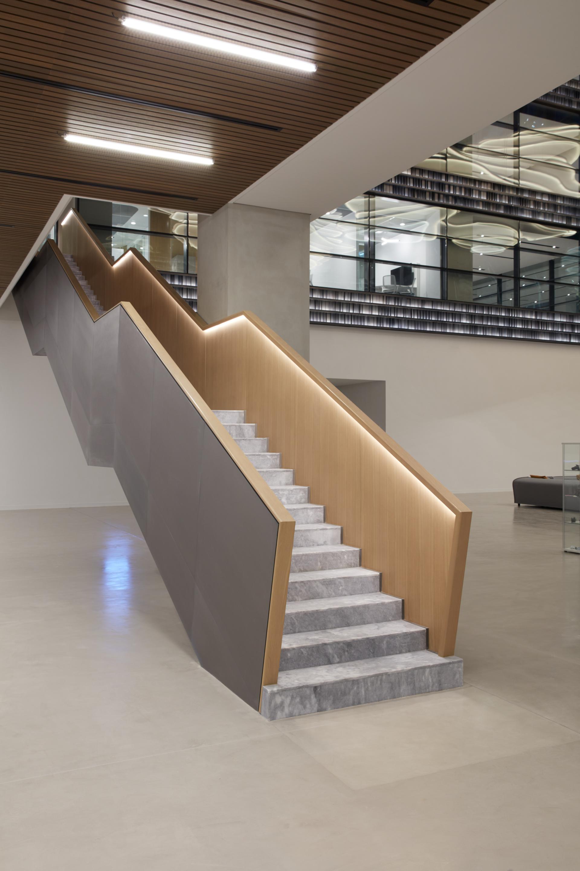Modern staircase design in the American University of Sharjah's Research Technology and Innovation Park, featuring wood and stone materials.