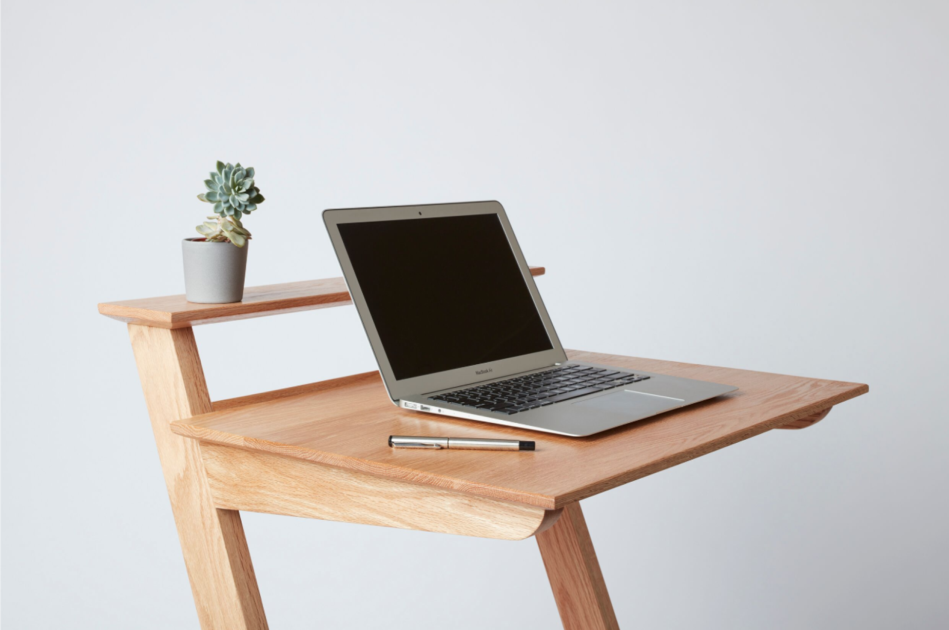 Sustainable wooden table featuring a laptop, pen, and small potted plant, designed by Building Crafts College students.