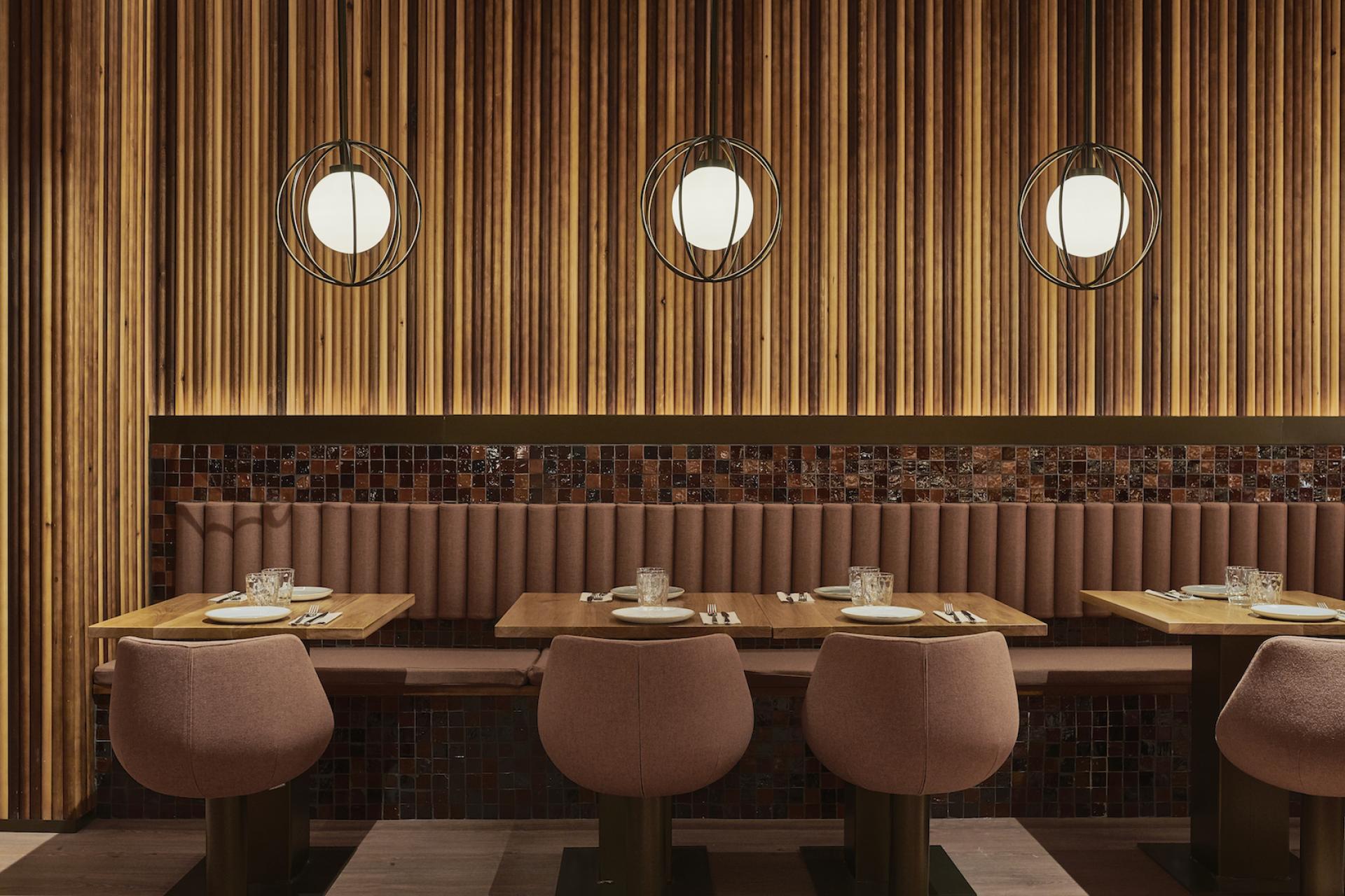 Elegant restaurant interior designed for Piur, featuring wooden wall paneling, modern lighting, and cozy dining seating.