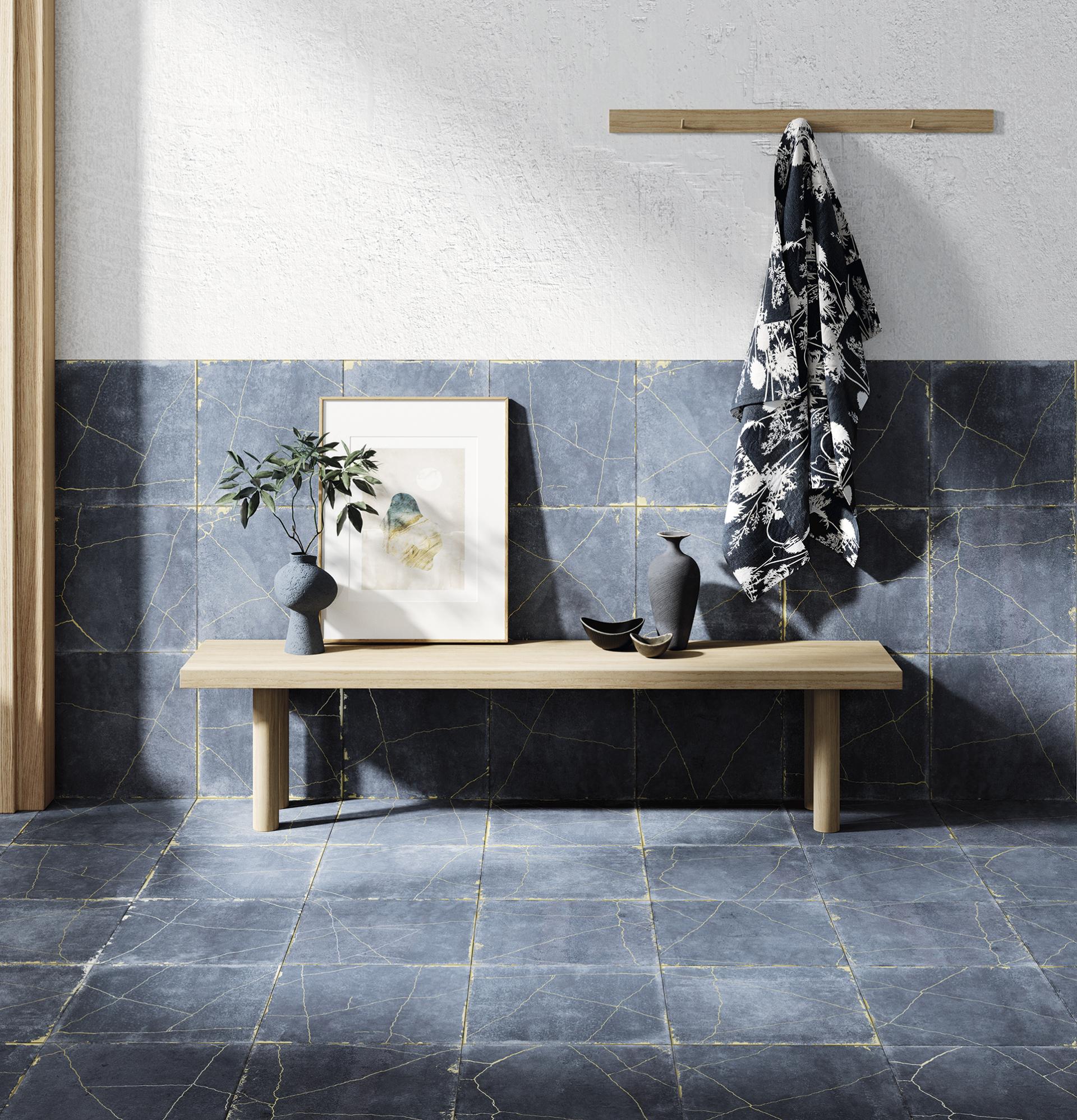 Modern interior featuring geometric blue tiles with golden veining, a wooden bench, decorative vases, and wall art.