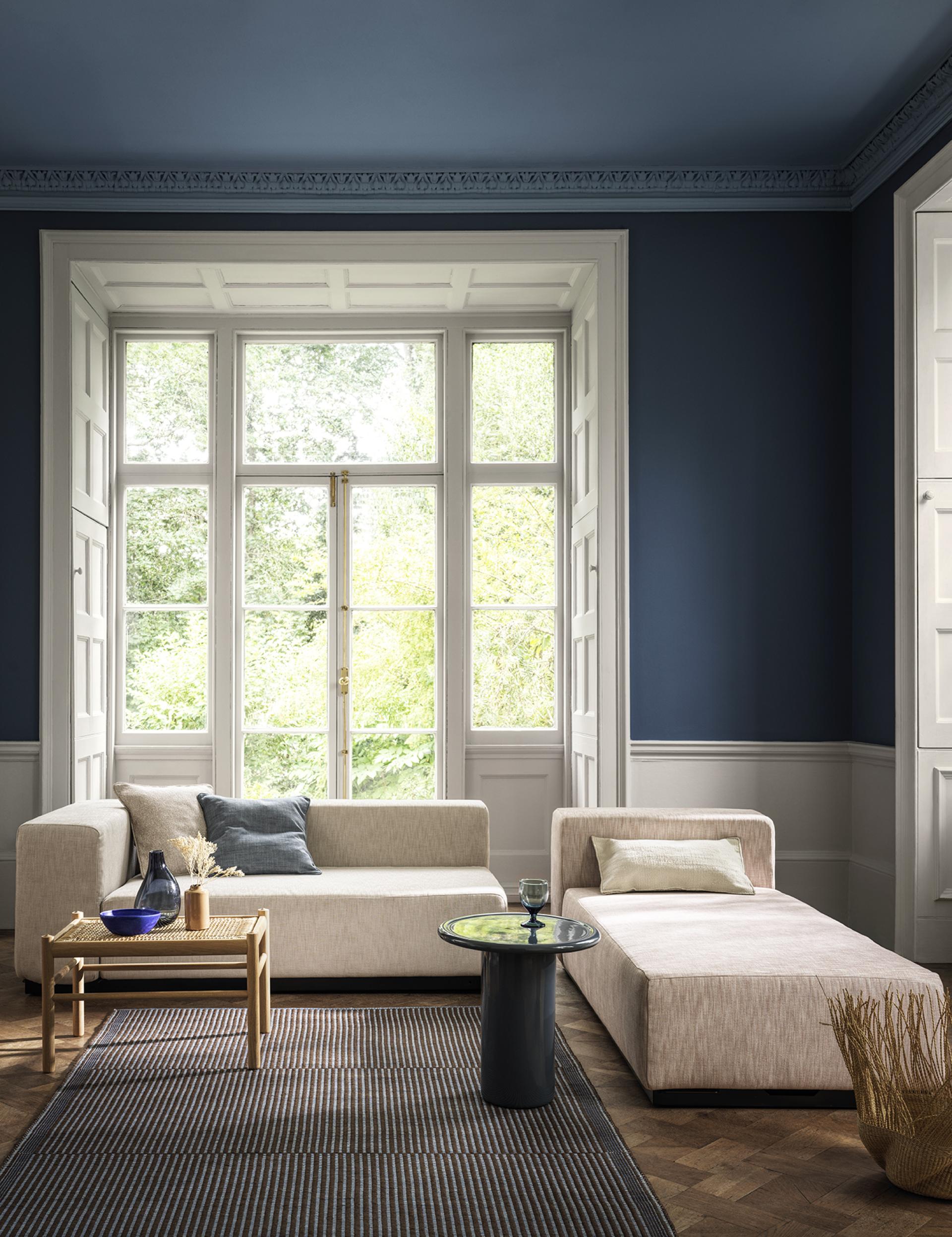 Stylish living room with blue accent wall, modern furniture, and natural light highlighting the serene atmosphere and decor trends.