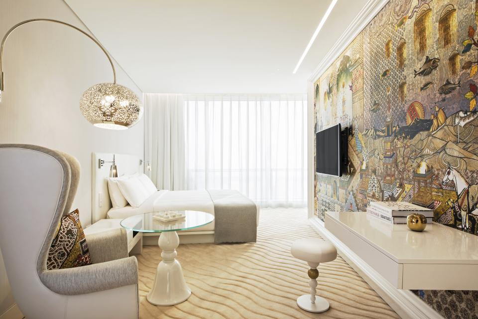 Luxurious hotel room at Mondrian Doha featuring a colorful mural, elegant furniture, and bright natural light.