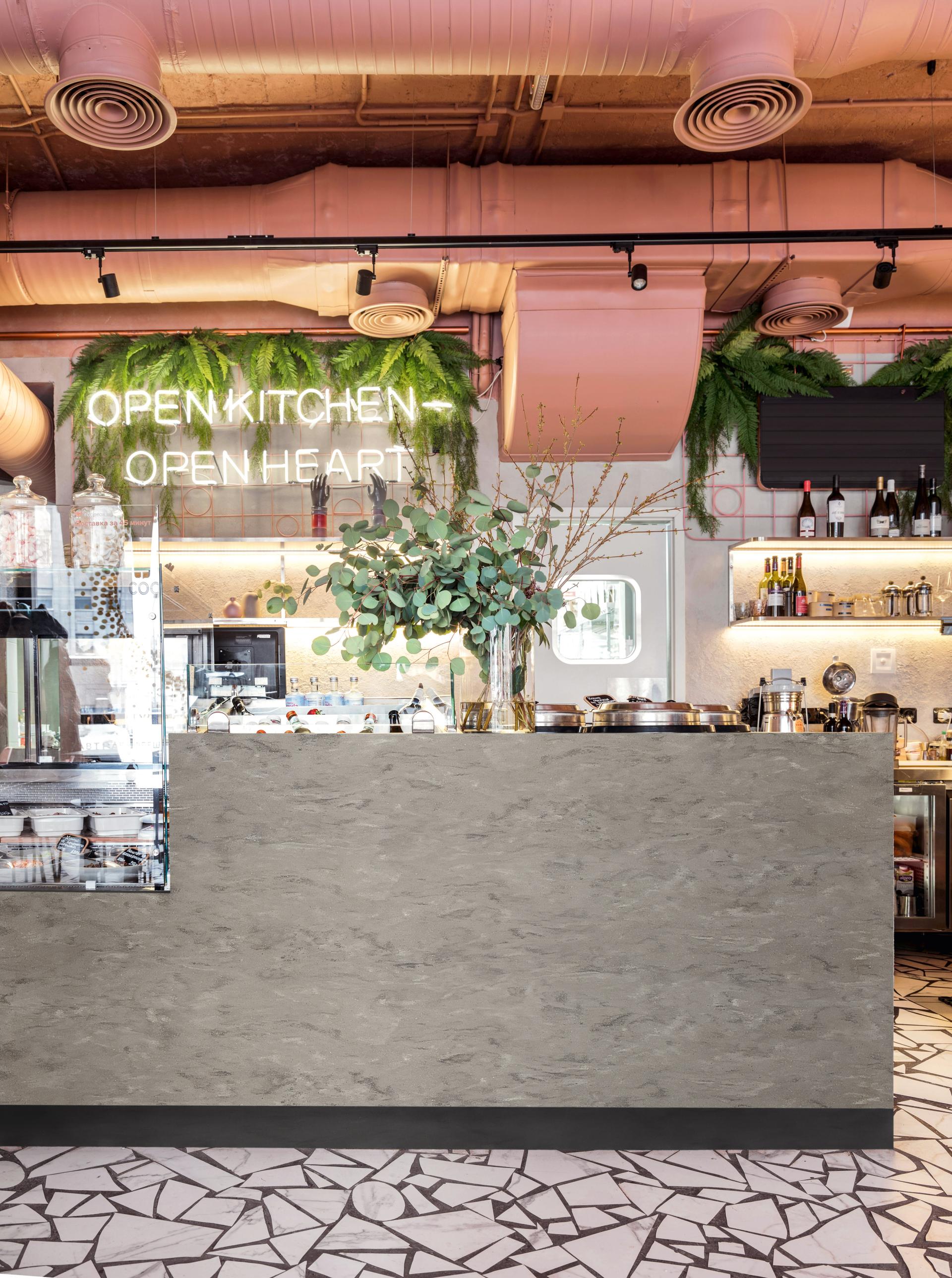 Modern café interior showcasing Corian® solid surface counter, lush green plants, and stylish decor with various kitchen appliances.
